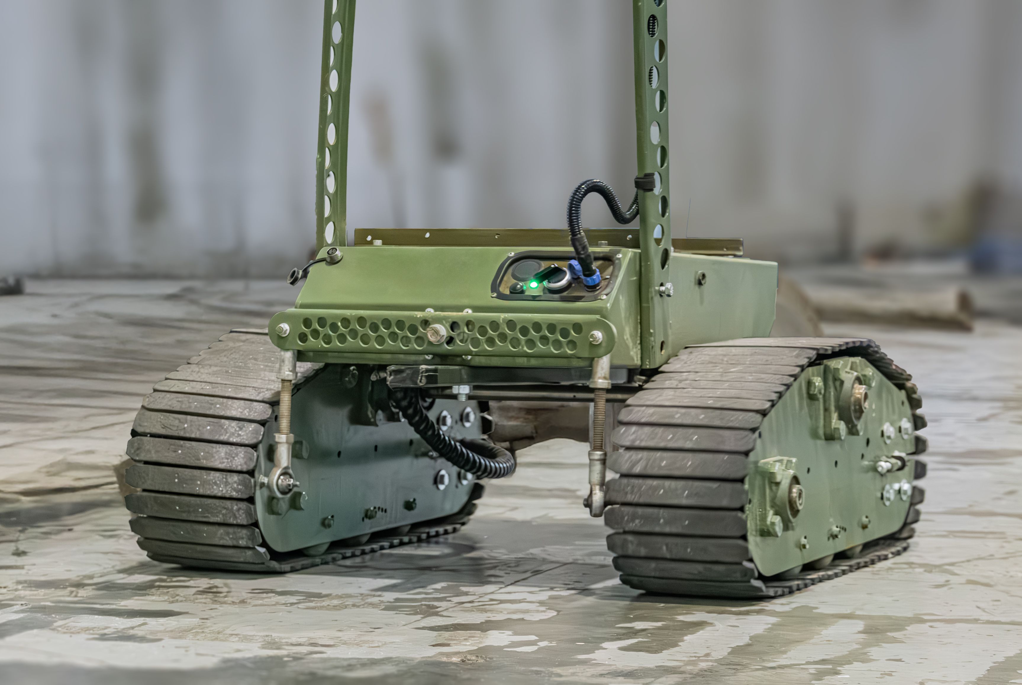 Indoor shot of a Ukrainian military mini robot on concrete, featuring four large wheel assemblies resembling all-terrain vehicle wheels Minimal background with a plain wall and indistinct objects O