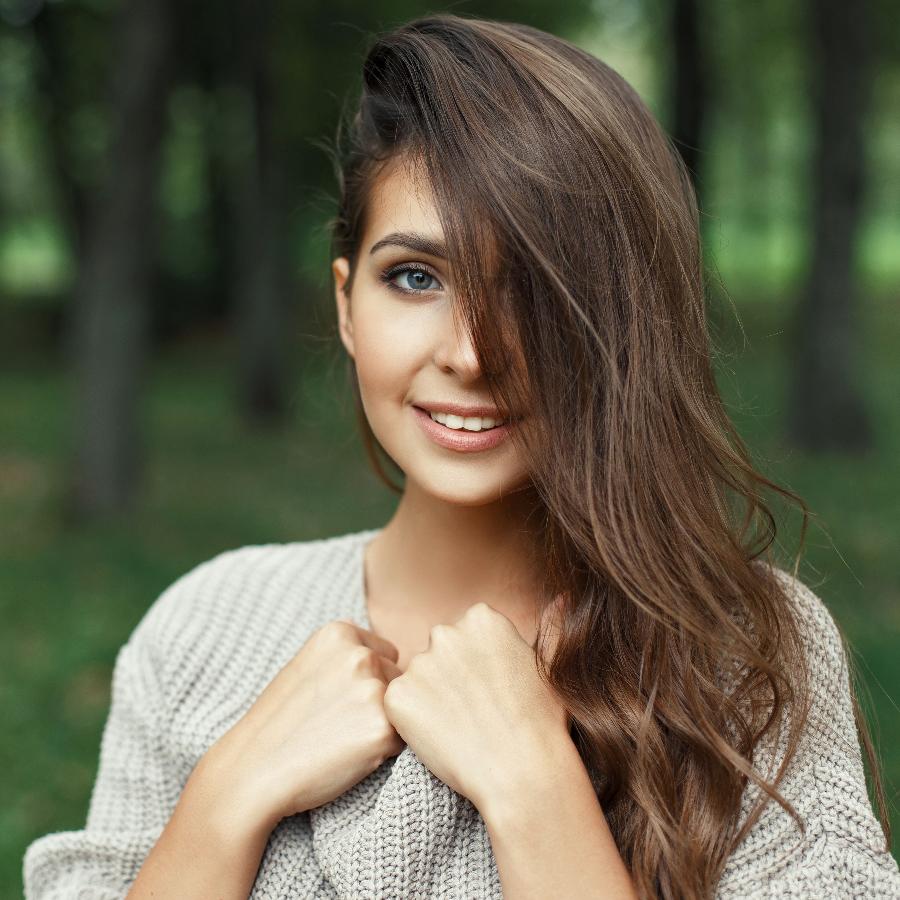 Beautiful portrait of a pretty young girl with the hairstyle smiling with a white smile in the park looking at the camera