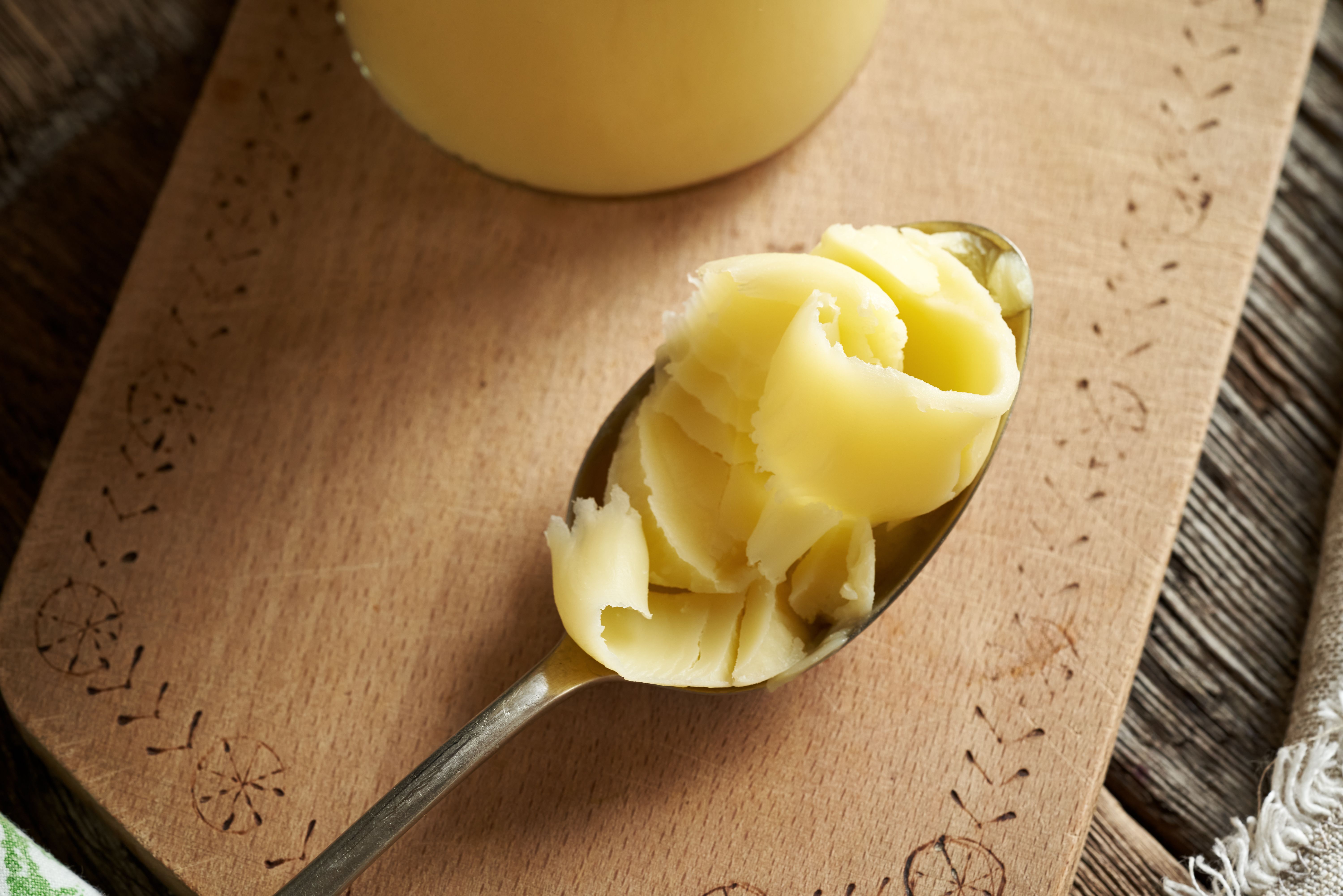 Ghee or clarified butter on a metal spoon on a table Ghee or clarified butter on a metal spoon on a table