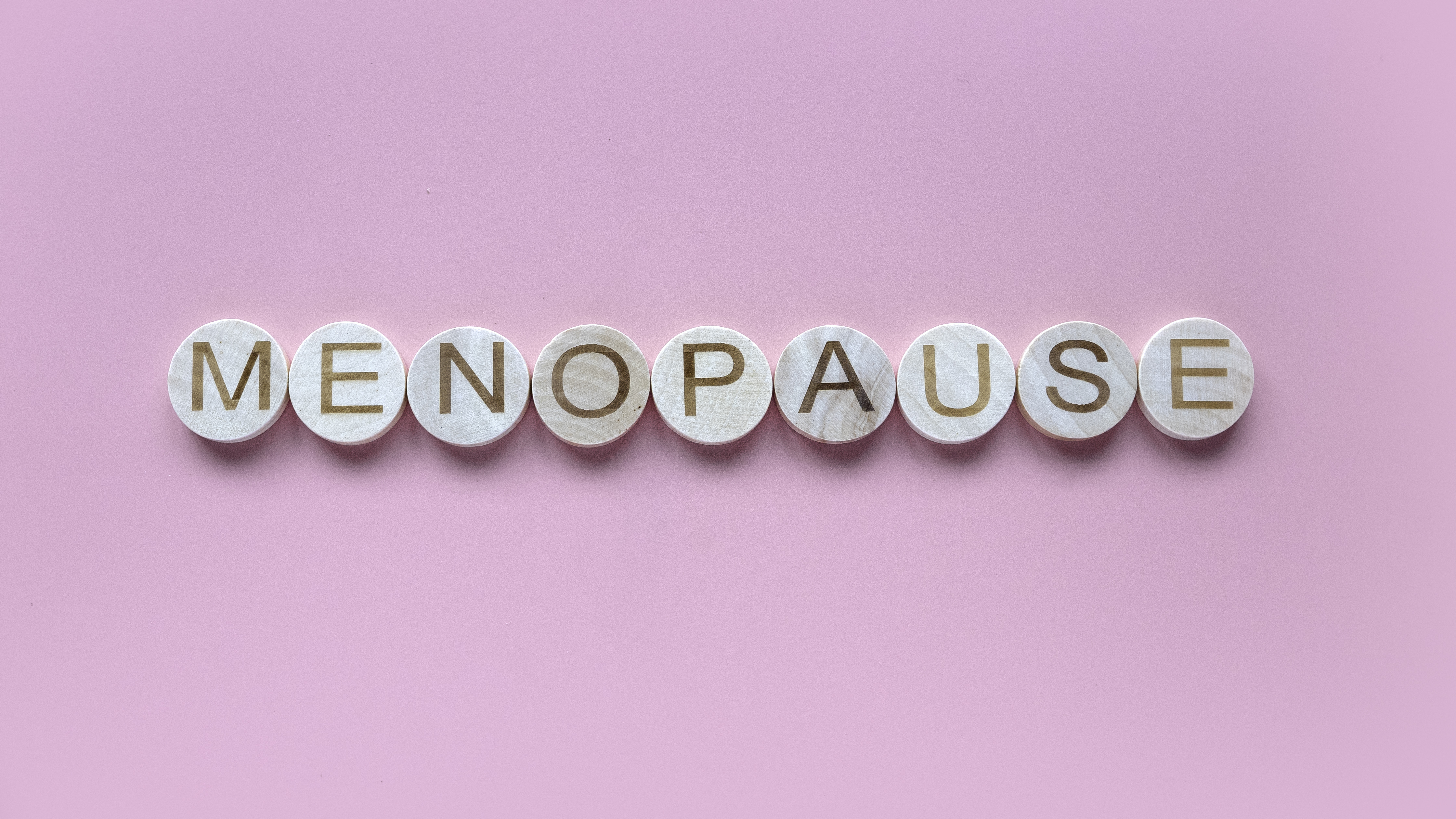 Alphabet form a word menopause. Healthcare and medical concept for women. Pink background.