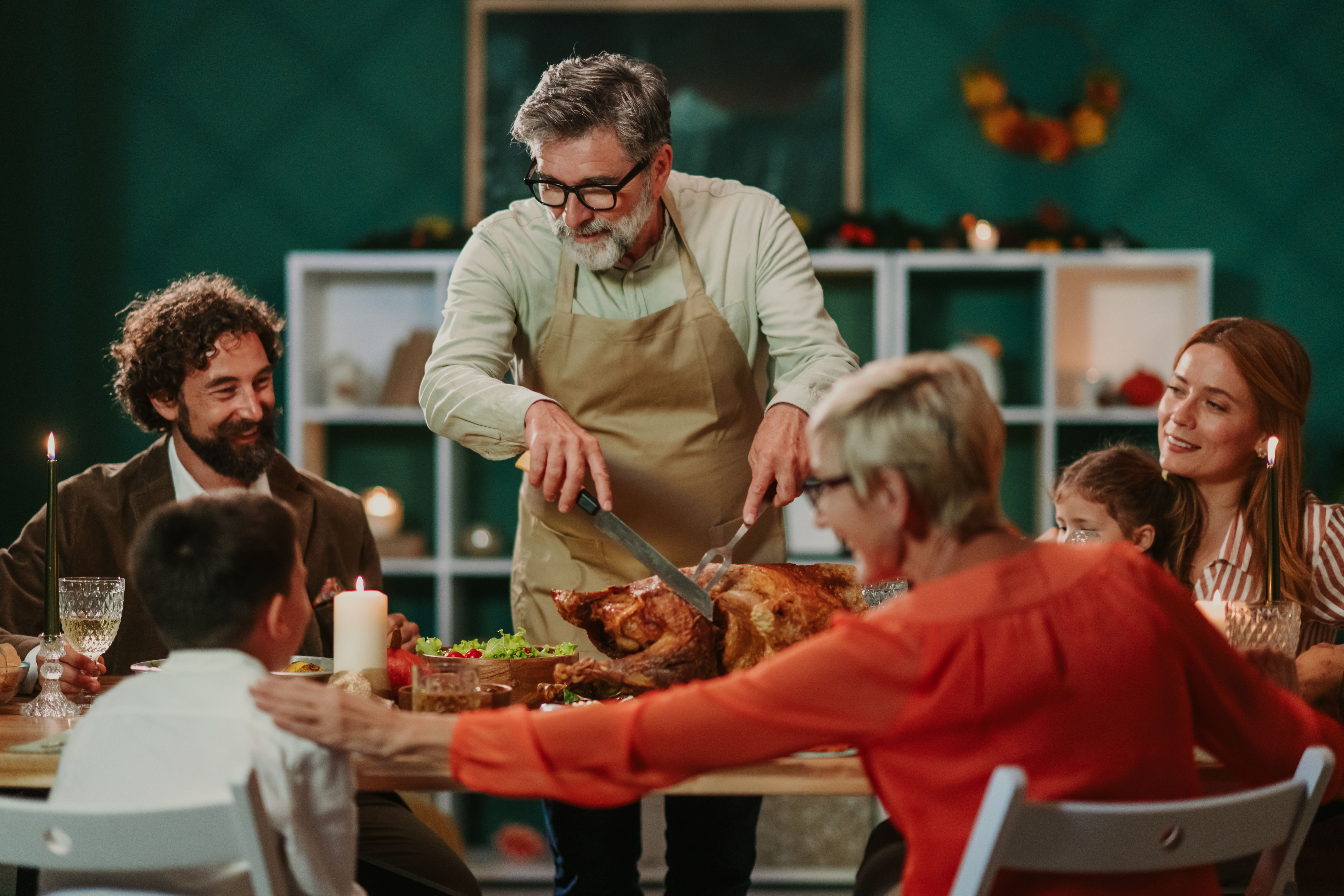 Grandfather carving thanksgiving turkey for his family dinner Grandfather carving thanksgiving turkey for his family dinner
