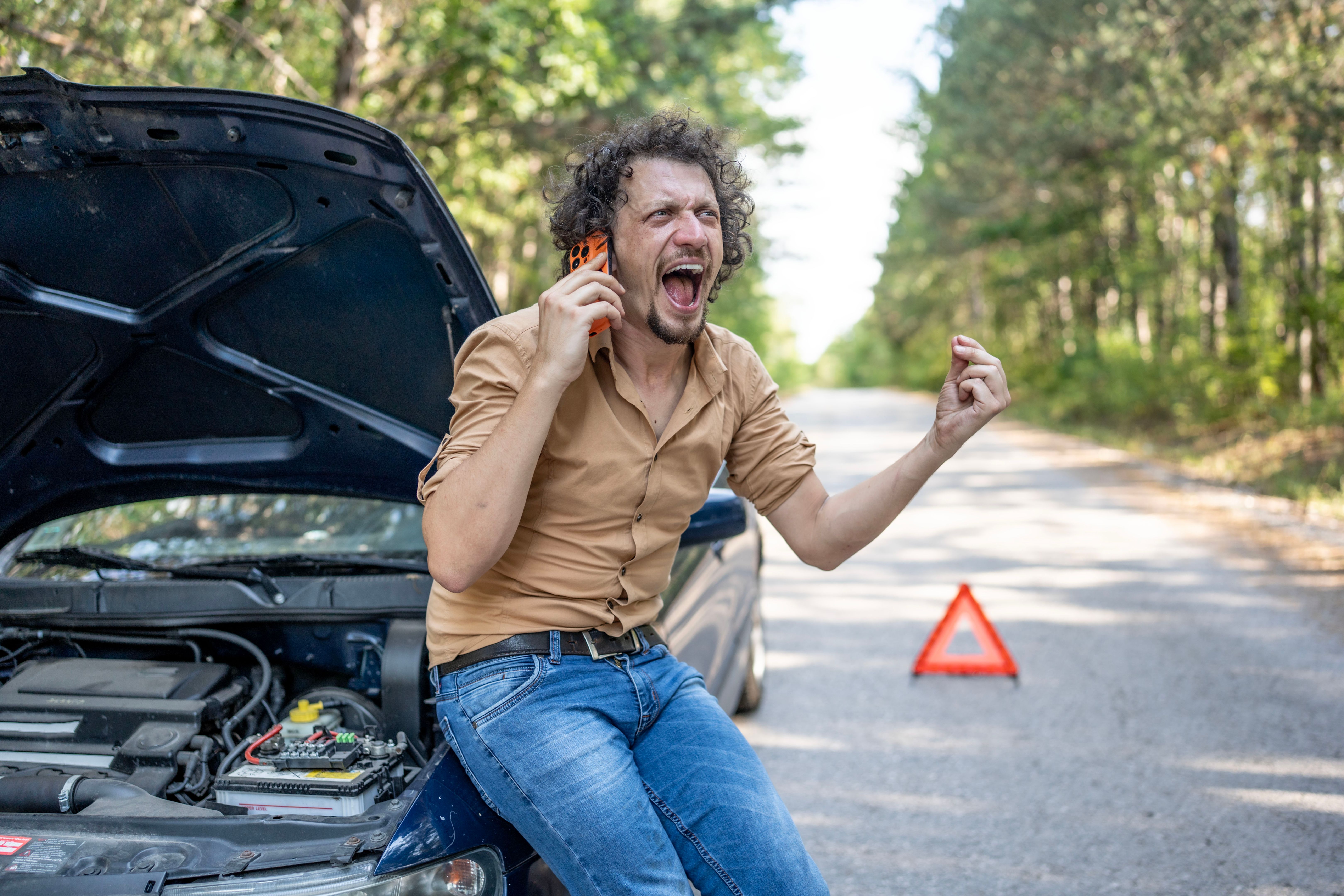 Frustrated Man Calling for Help with Broken Car on Countryside Road