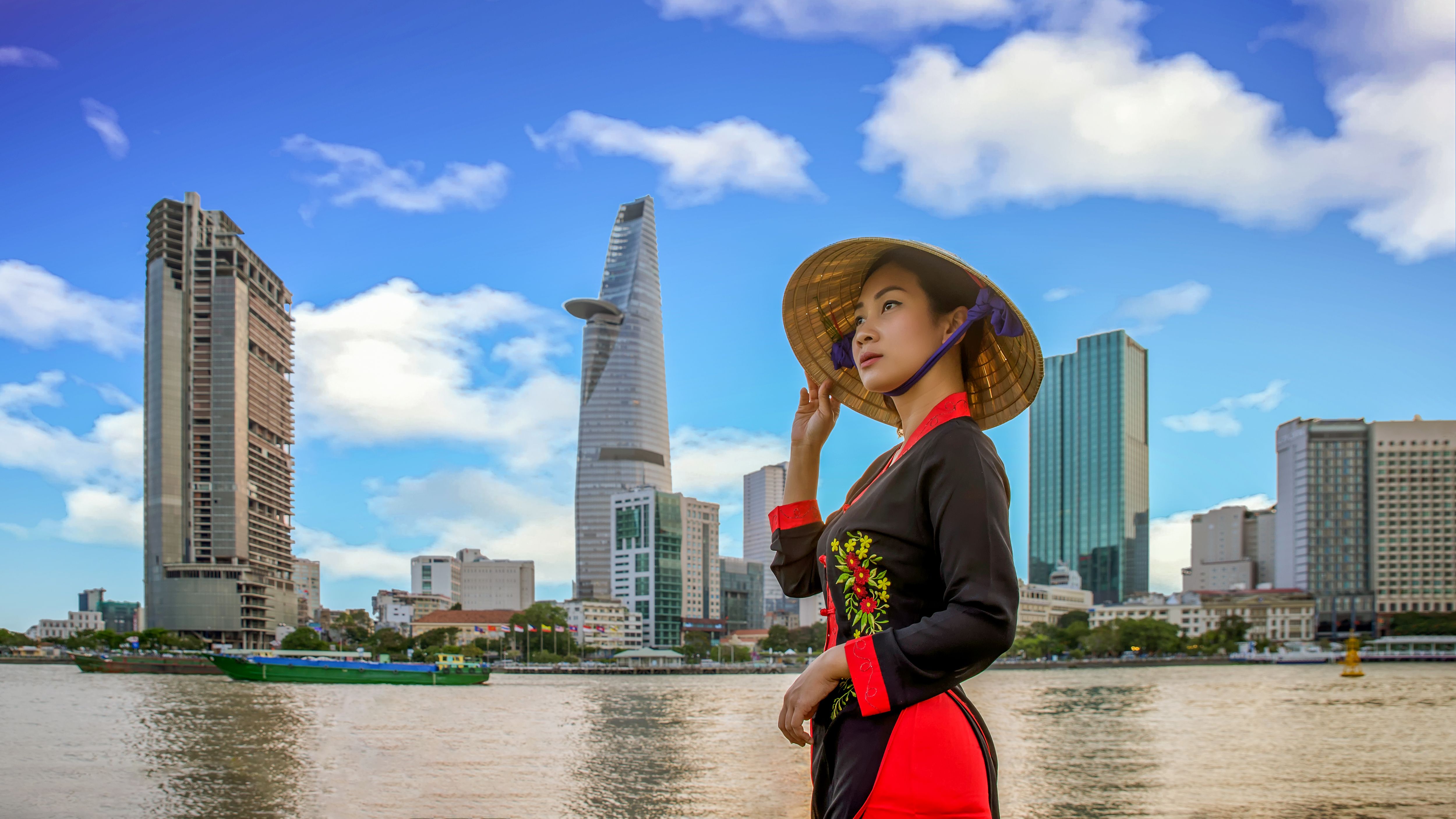 Young vietnamese woman with view of Ho Chi Minh City skyline and the Saigon River, Vietnam