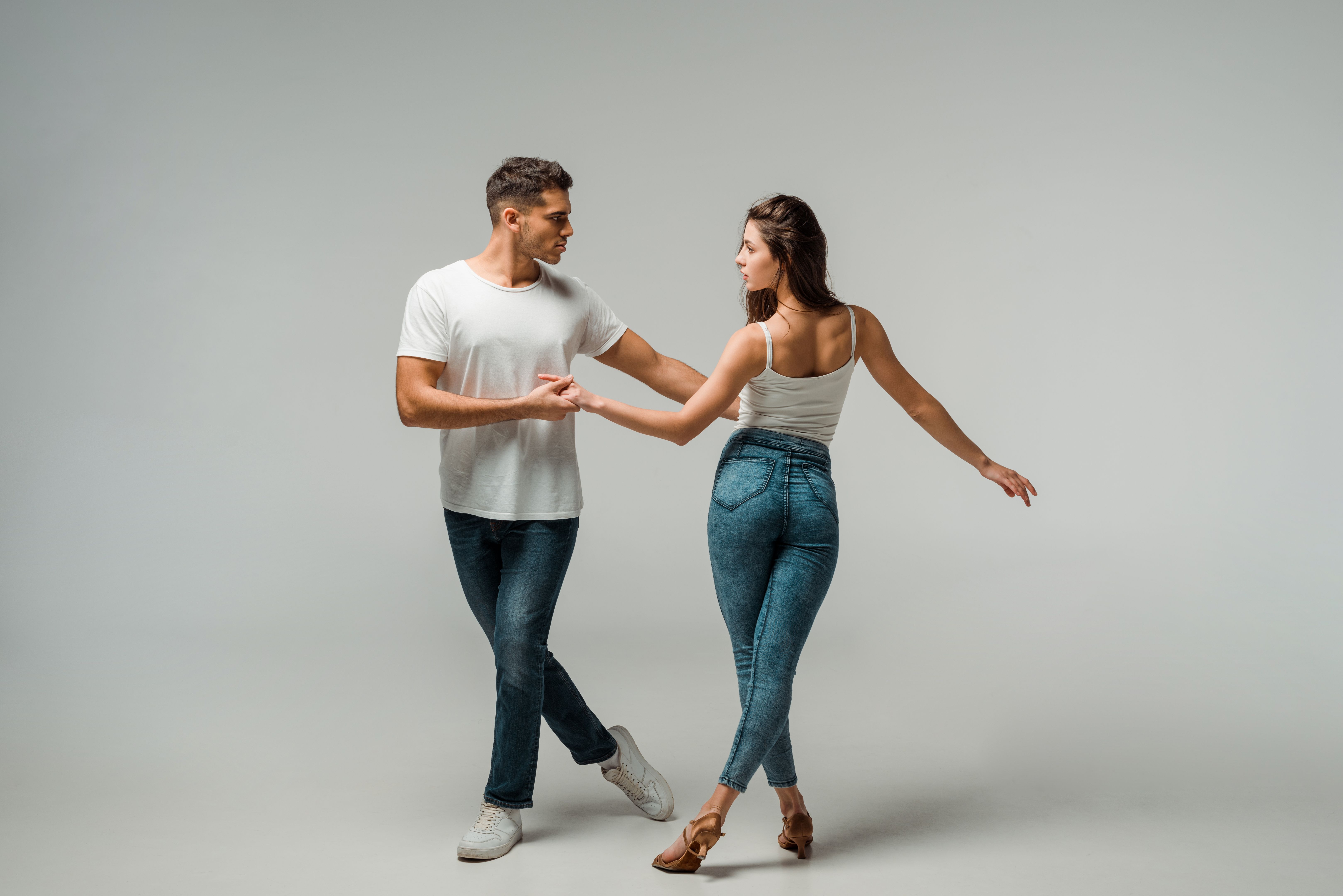 dancers in denim jeans dancing bachata on grey background dancers in denim jeans dancing bachata on grey background