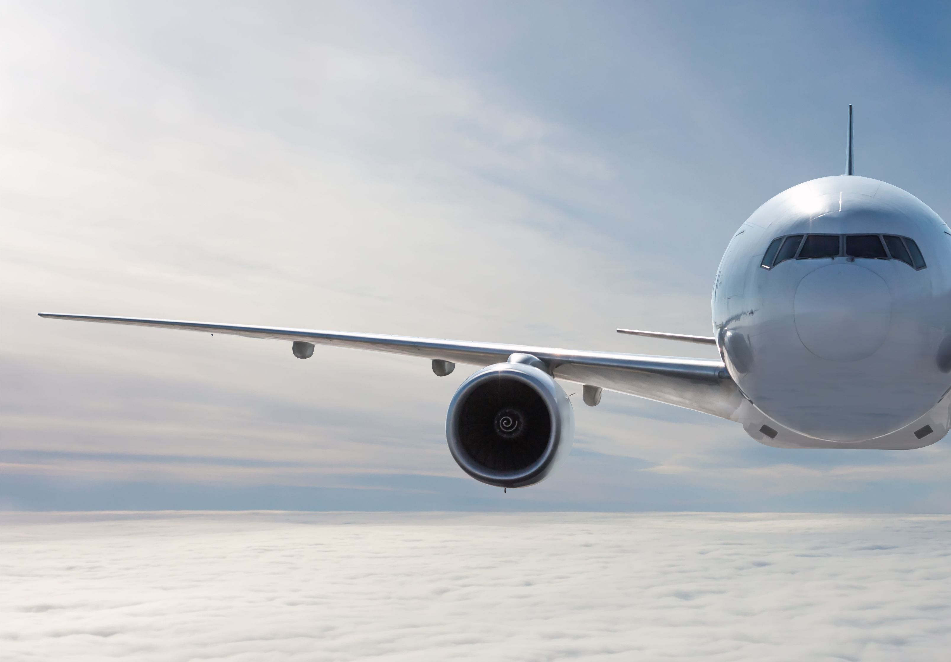 Front view of the white wide body passenger airplane flies in the air above the clouds Front view of the white wide body passenger airplane flies in the air above the clouds