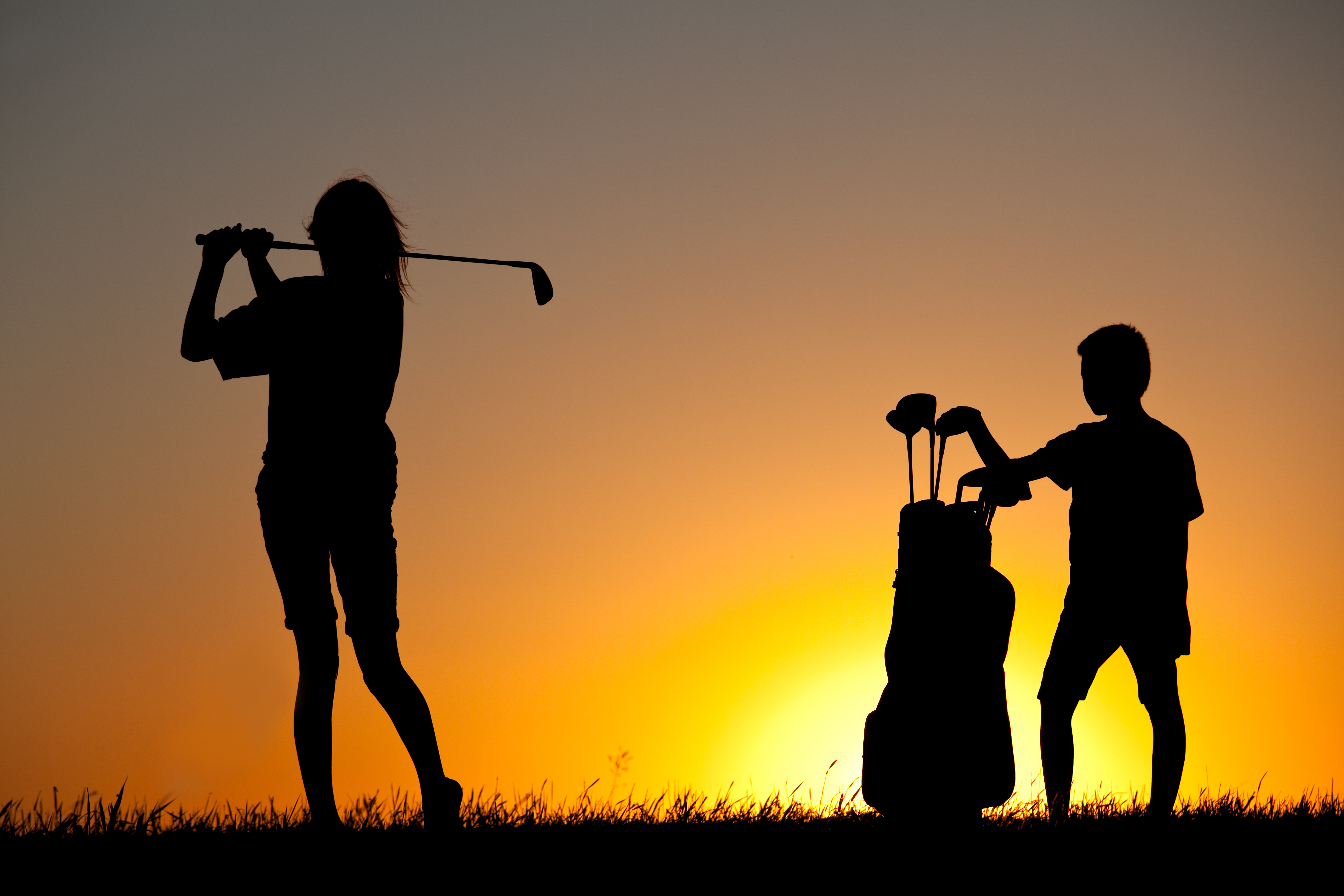 Junior Girl Golfing Silhouette with Young Caddie Junior Girl Golfing Silhouette with Young Caddie