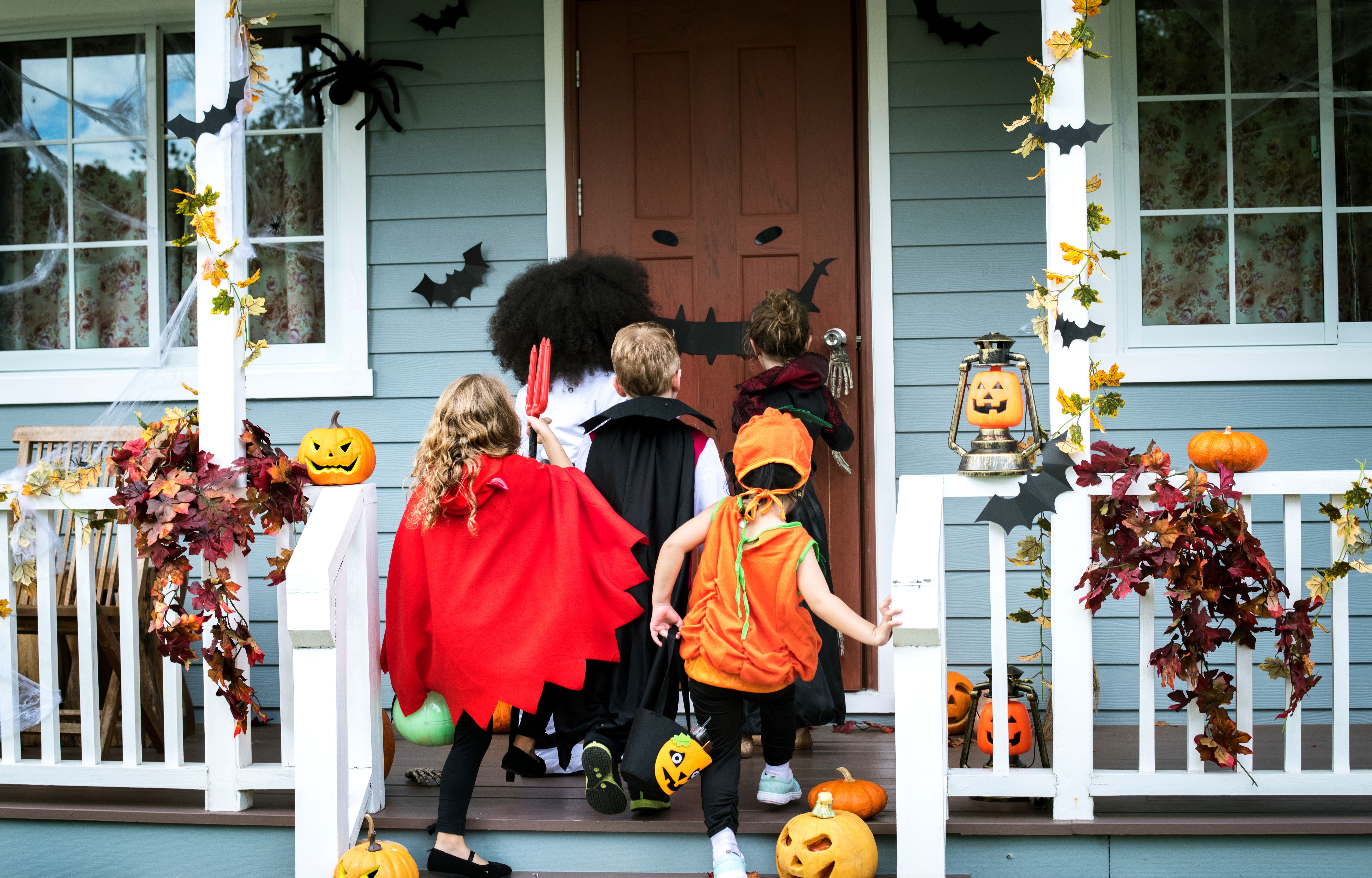 Five young kids in costumes trick or treating during Halloween at the front door of a fall decorated home. Halloween in Phoenix — friendly neighbors, and sweet treats all around. Happy All Hallows’ Eve from Train Station Pest Elimination! 