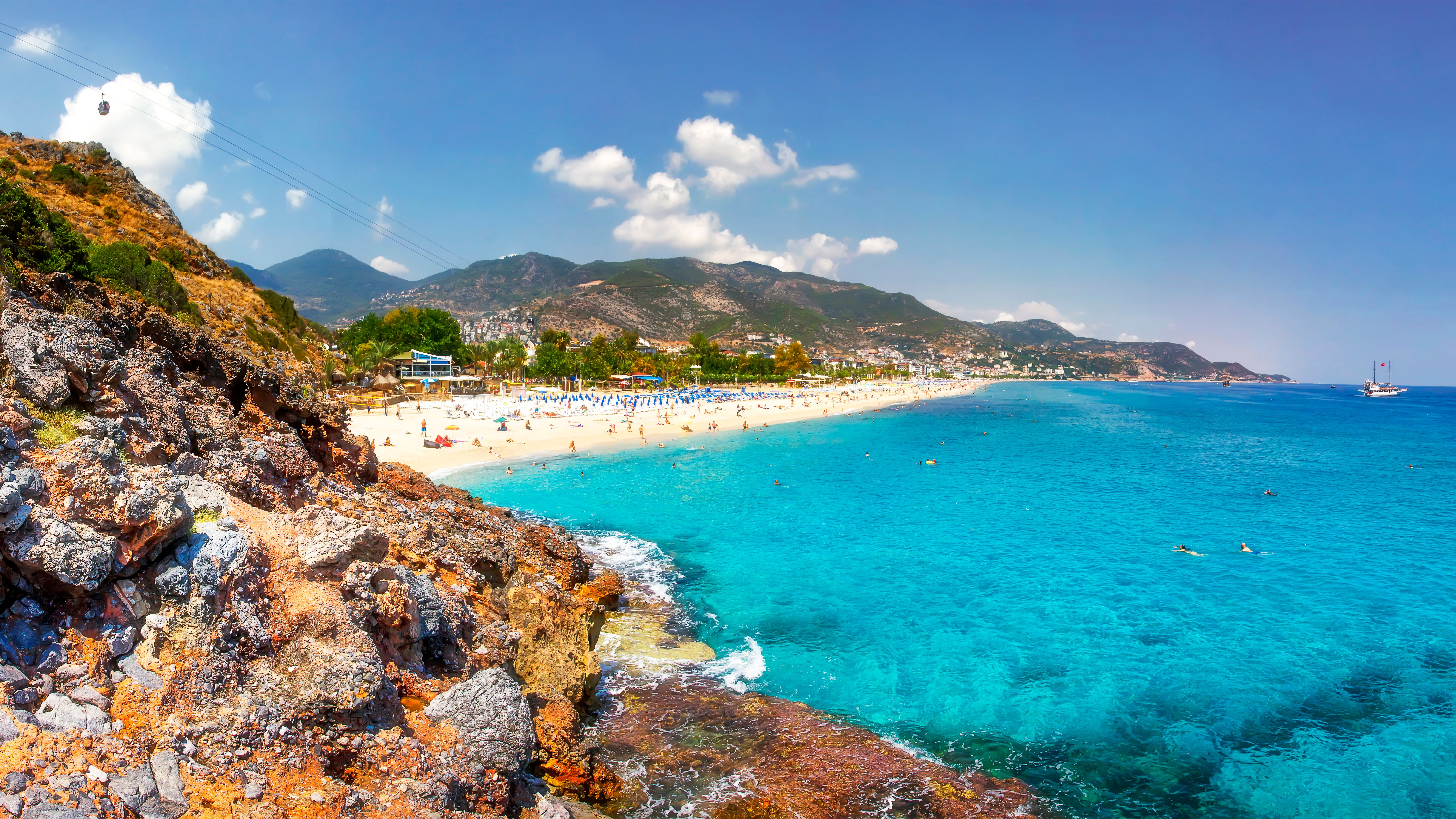 Sea landscape of the Mediterranean on clear sunny day. Sandy beach, rocks, blue sky, mountains and sea. Paradise Bay in Alanya. Tropical resort for summer holidays. coastline of sea resort beach.
