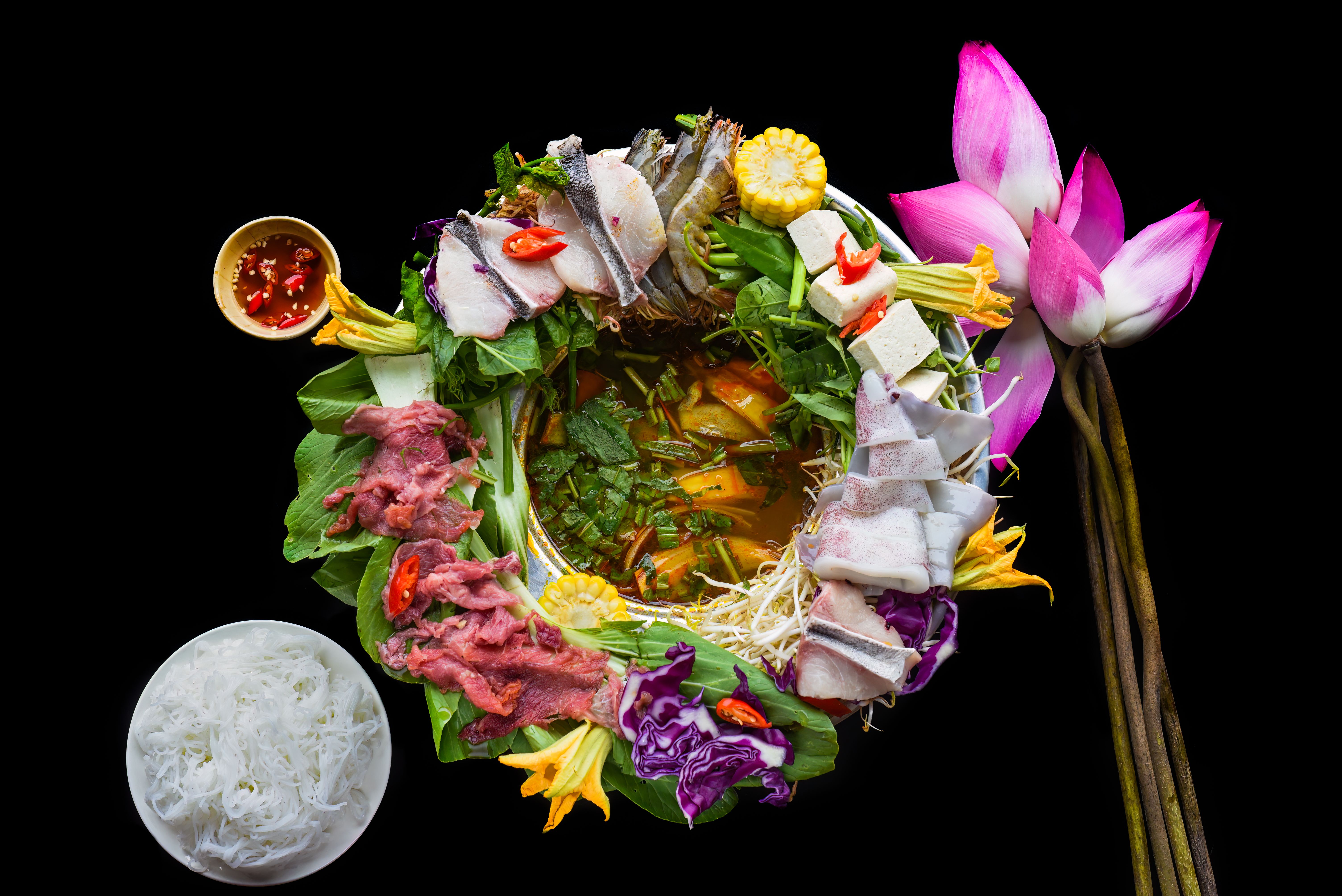 Vietnamese hot pot with raw seafood on black background