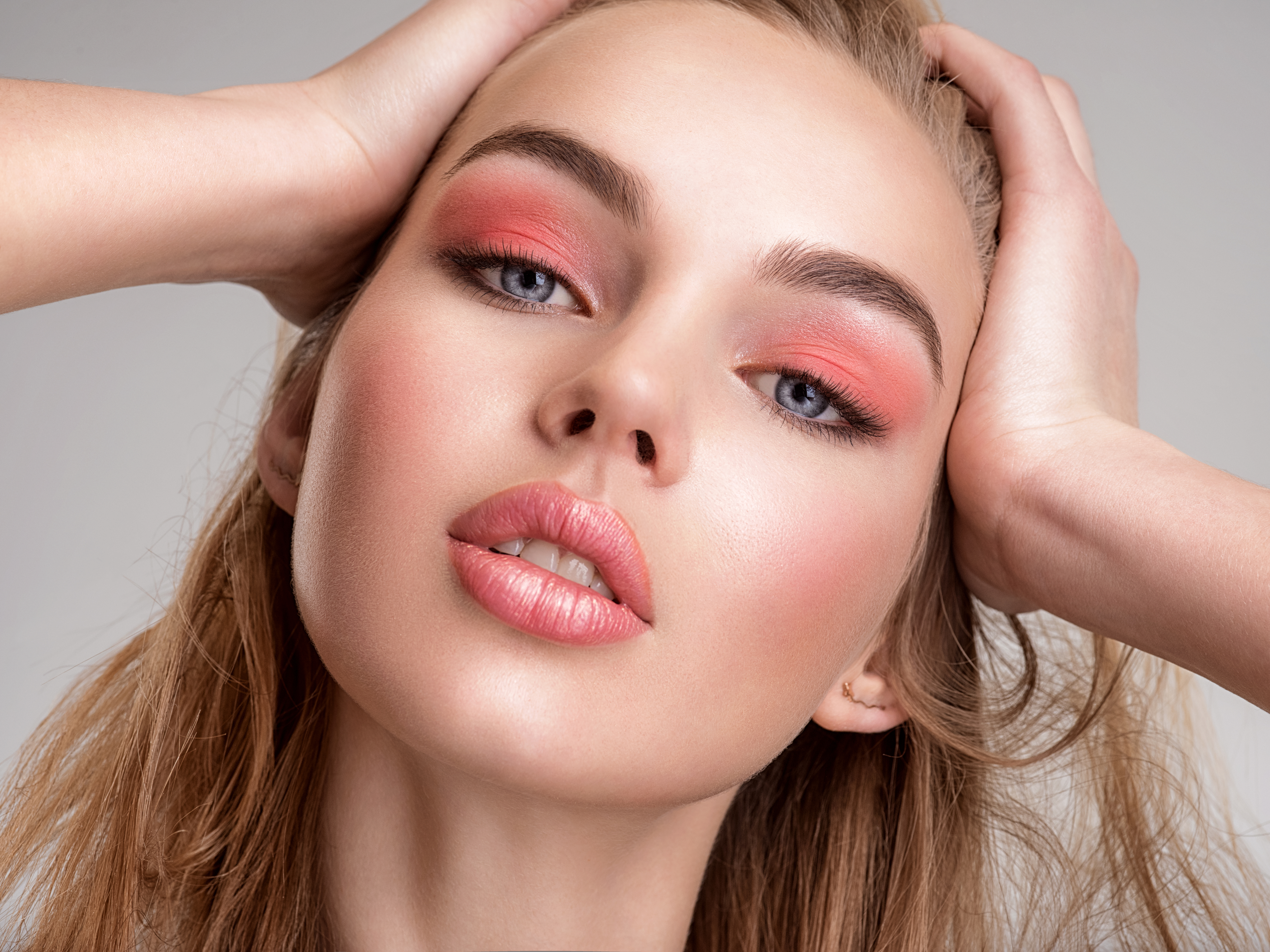 Portrait of a beautiful woman with a coral color makeup. Attractive blond  girl with  bright fashion make-up, posing at studio. Beautiful female face. Closeup portrait of pretty lady. Fashion model.