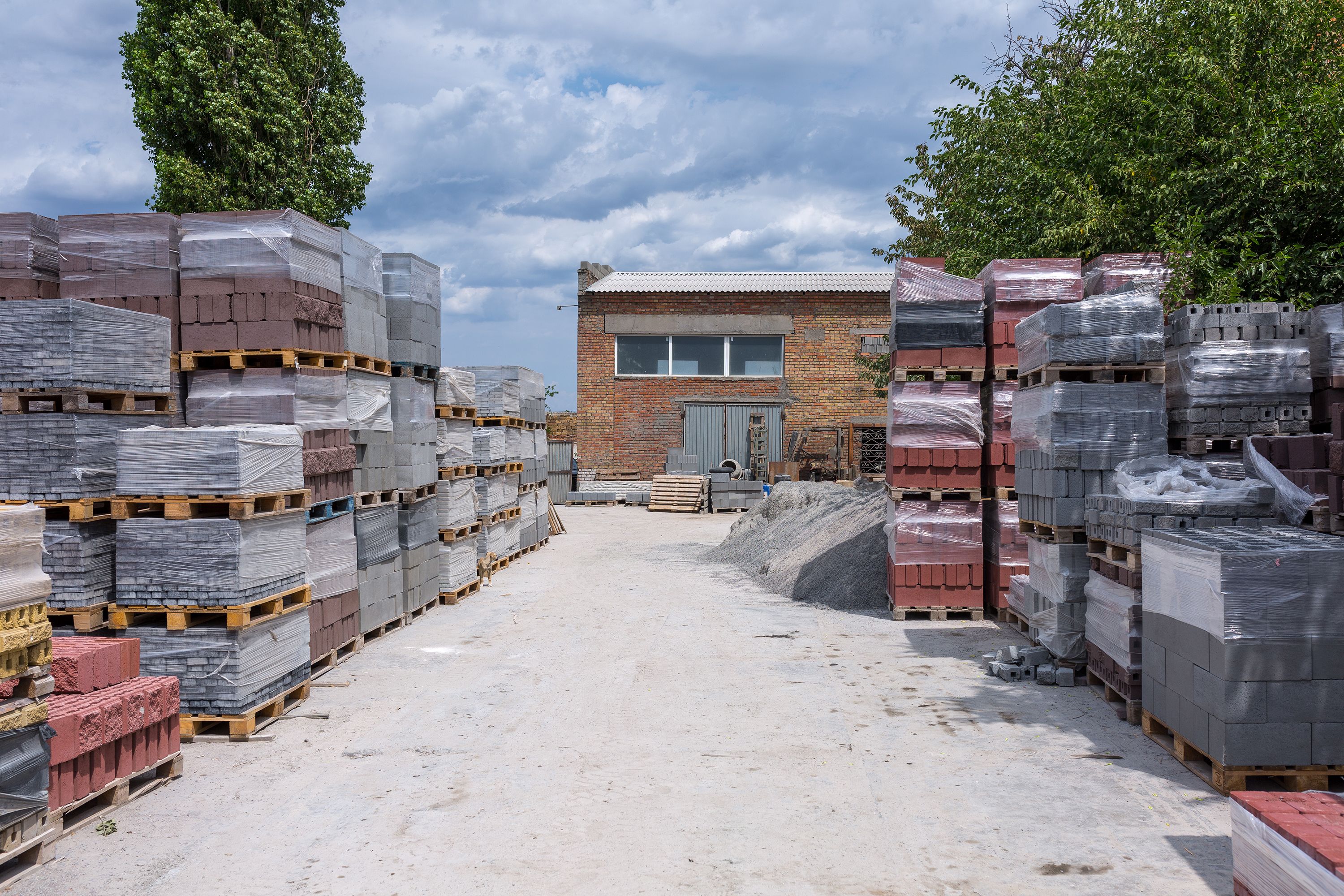 Industrial production of building cement pressed materials. High quality hollow concrete block or cement brick and paving stones. Finished products on pallets packed in film are waiting to be shipped.