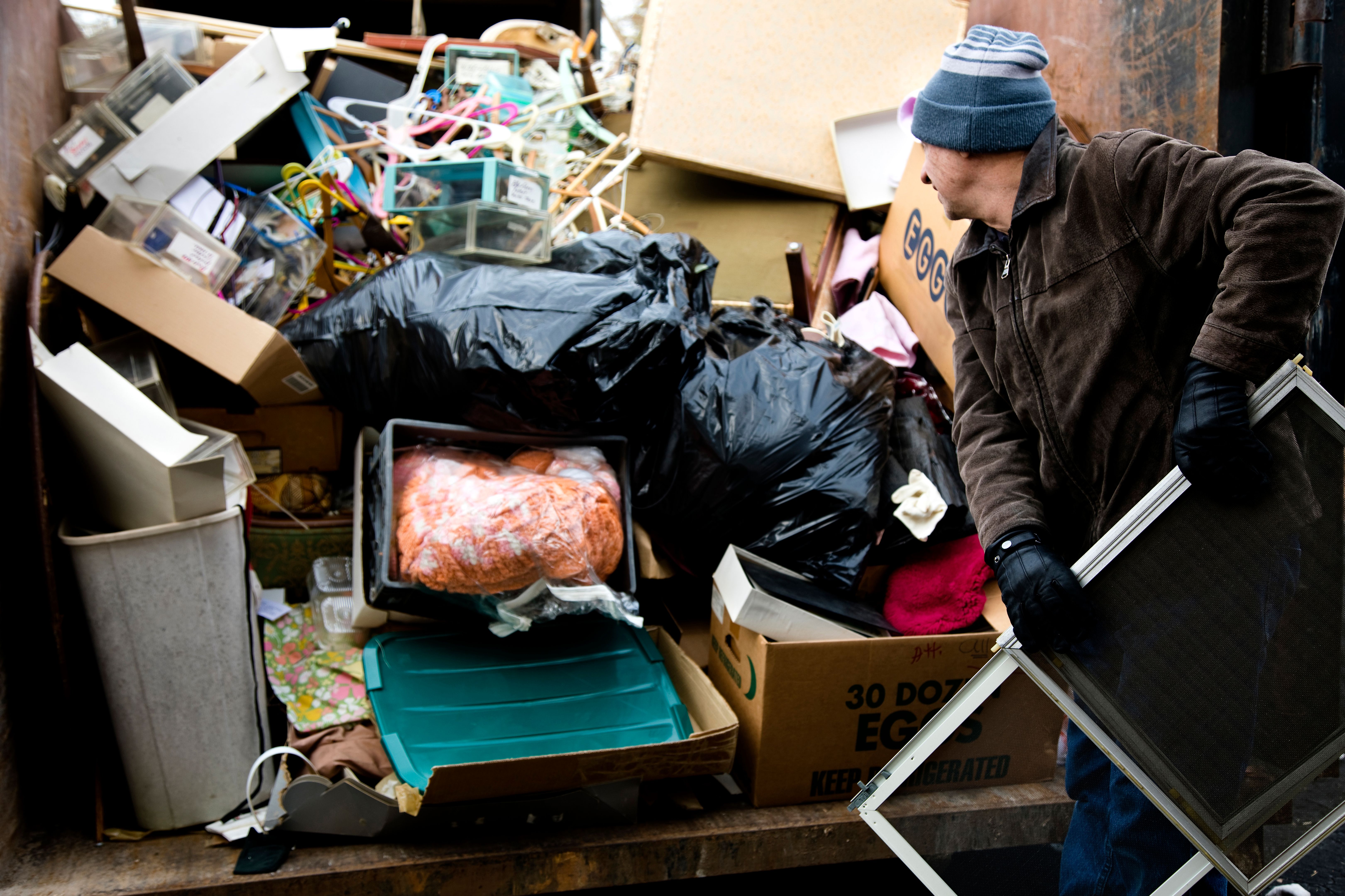 Workman loading junk in dumpster Workman loading junk in dumpster