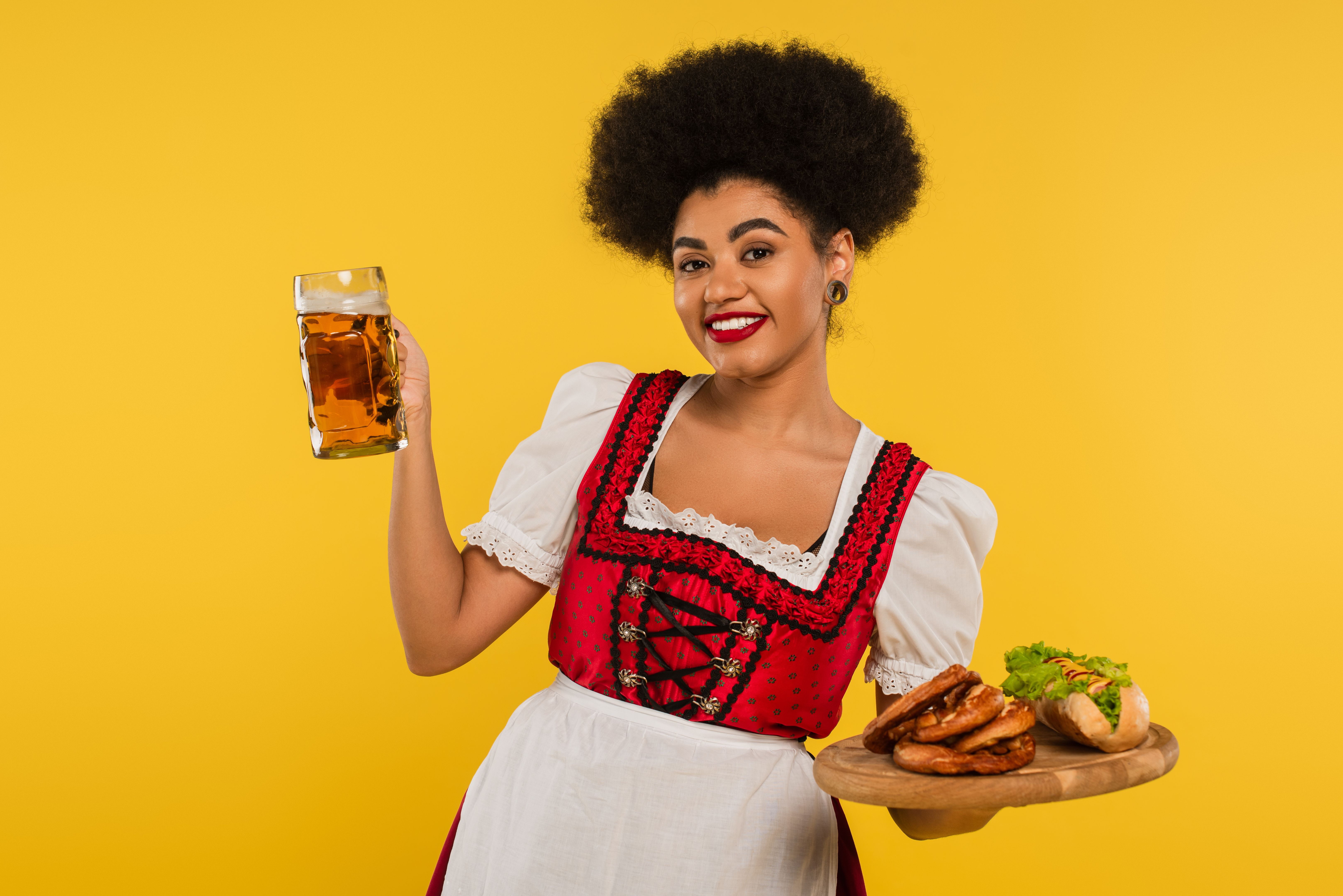 A cheerful young woman in traditional Bavarian attire serves Beer Fest delights