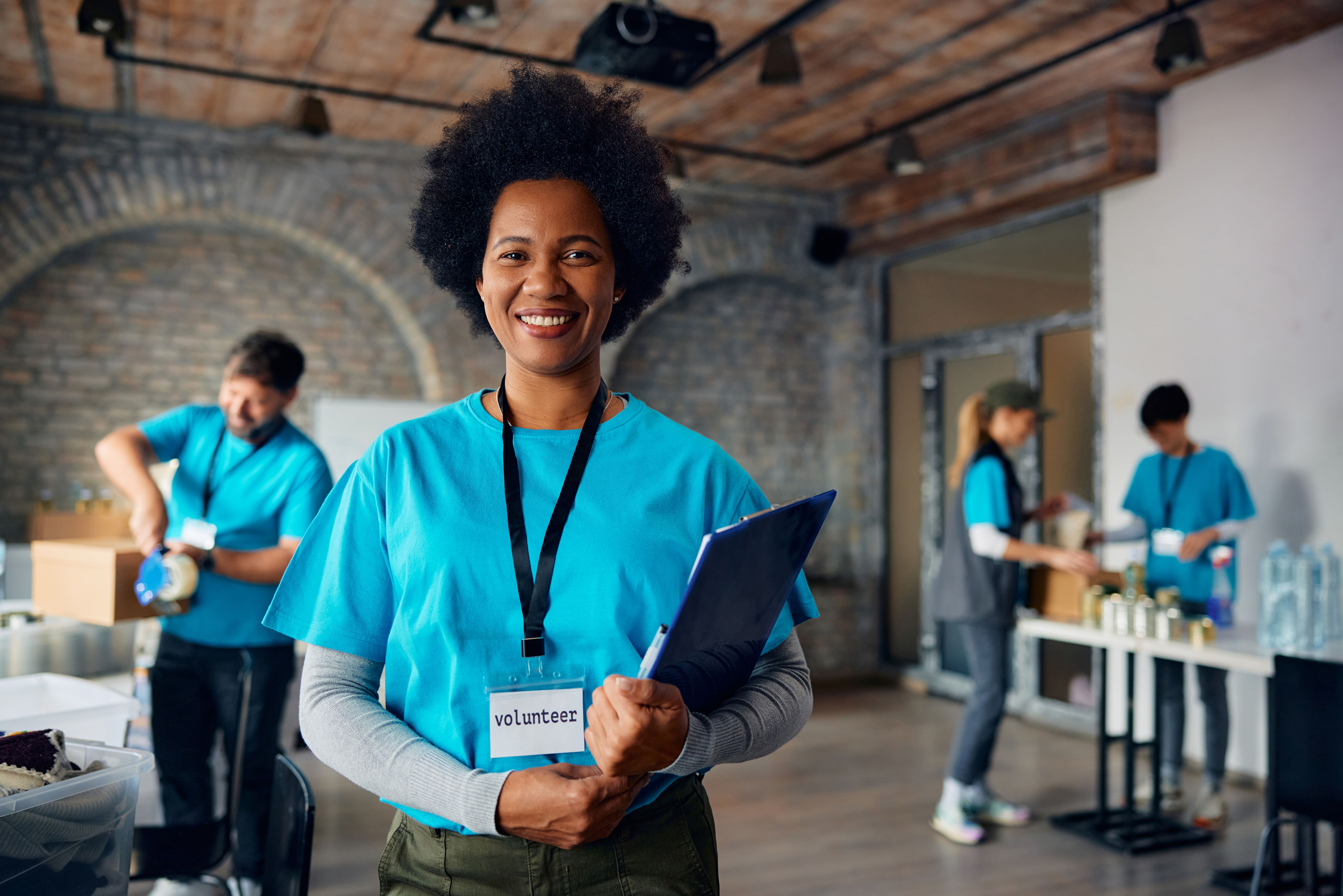 Happy black woman working as volunteer at donation center and looking at camera.