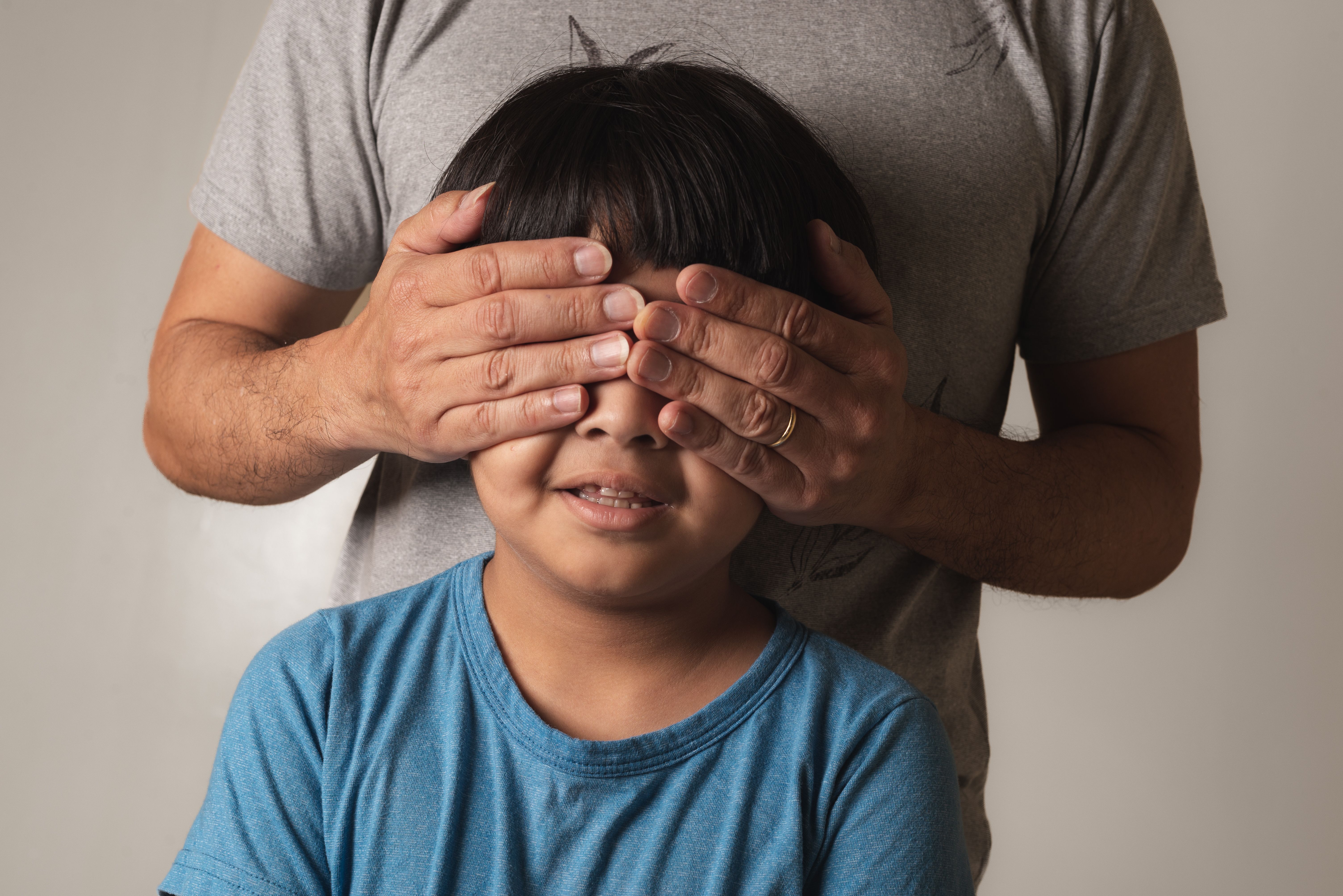 Portrait of son with eyes covered by his father's hands Portrait of son with eyes covered by his father's hands