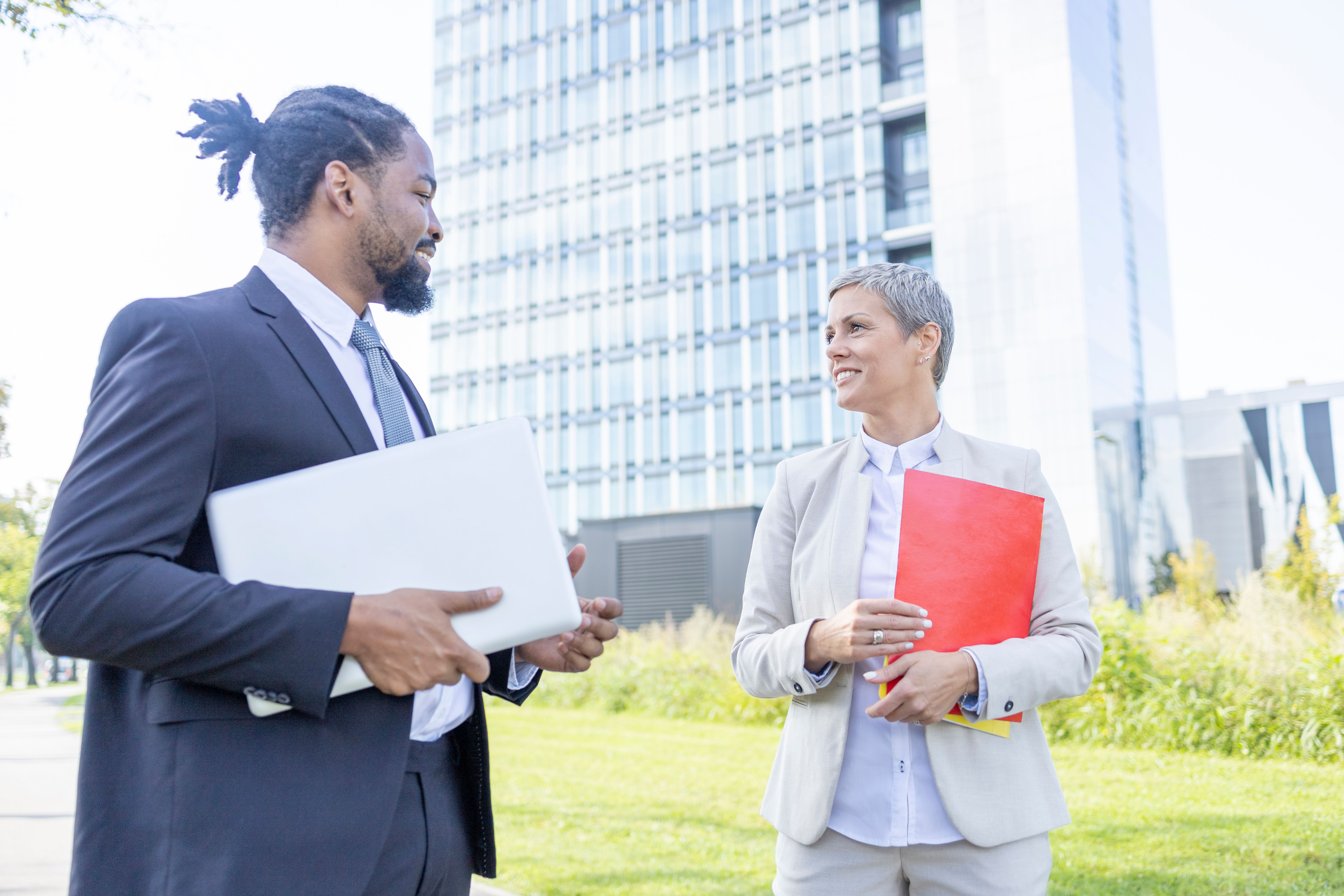 Happy business woman meeting with coworker outdoors