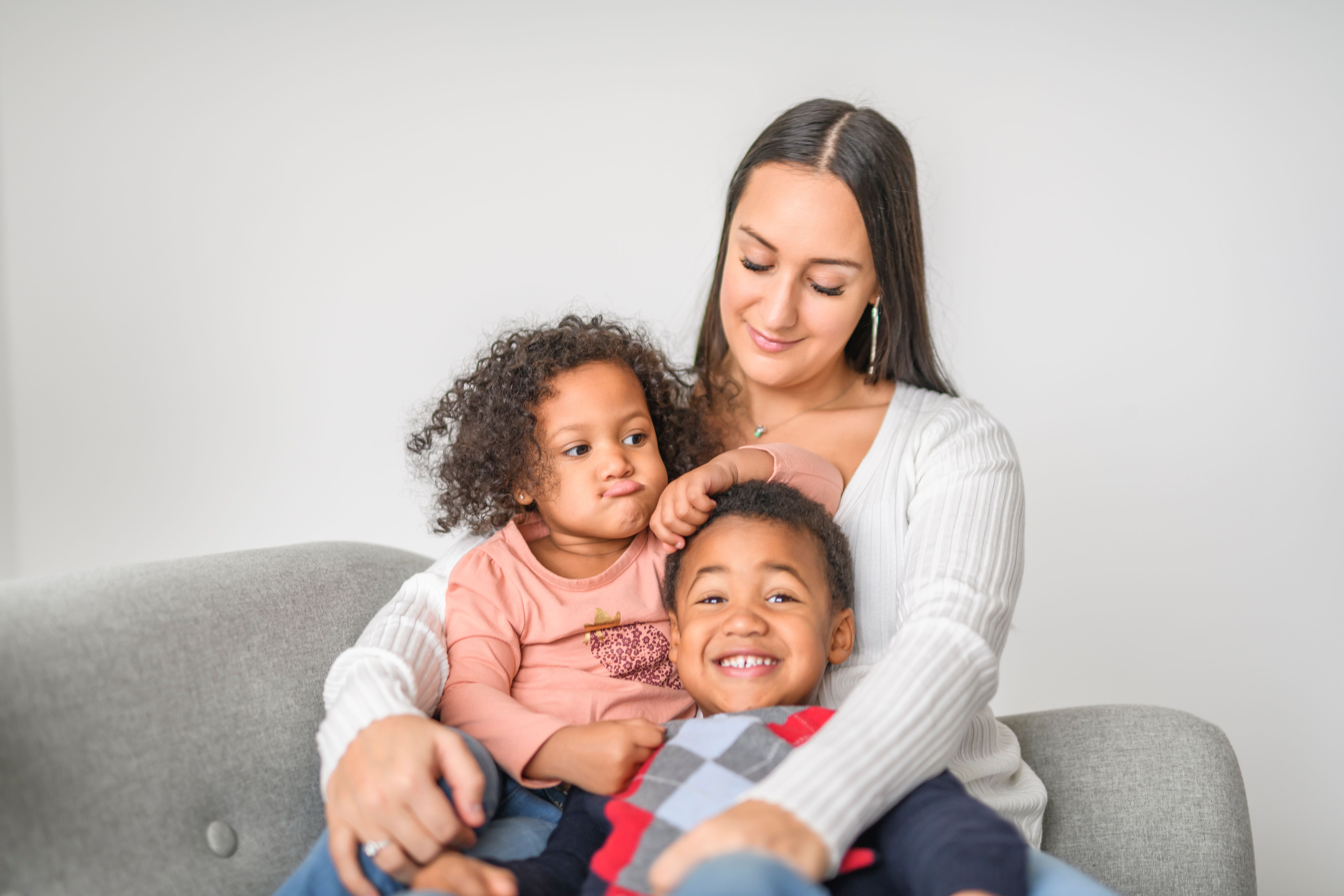 family with boy and girl child posing on photo shooting, sitting on couch