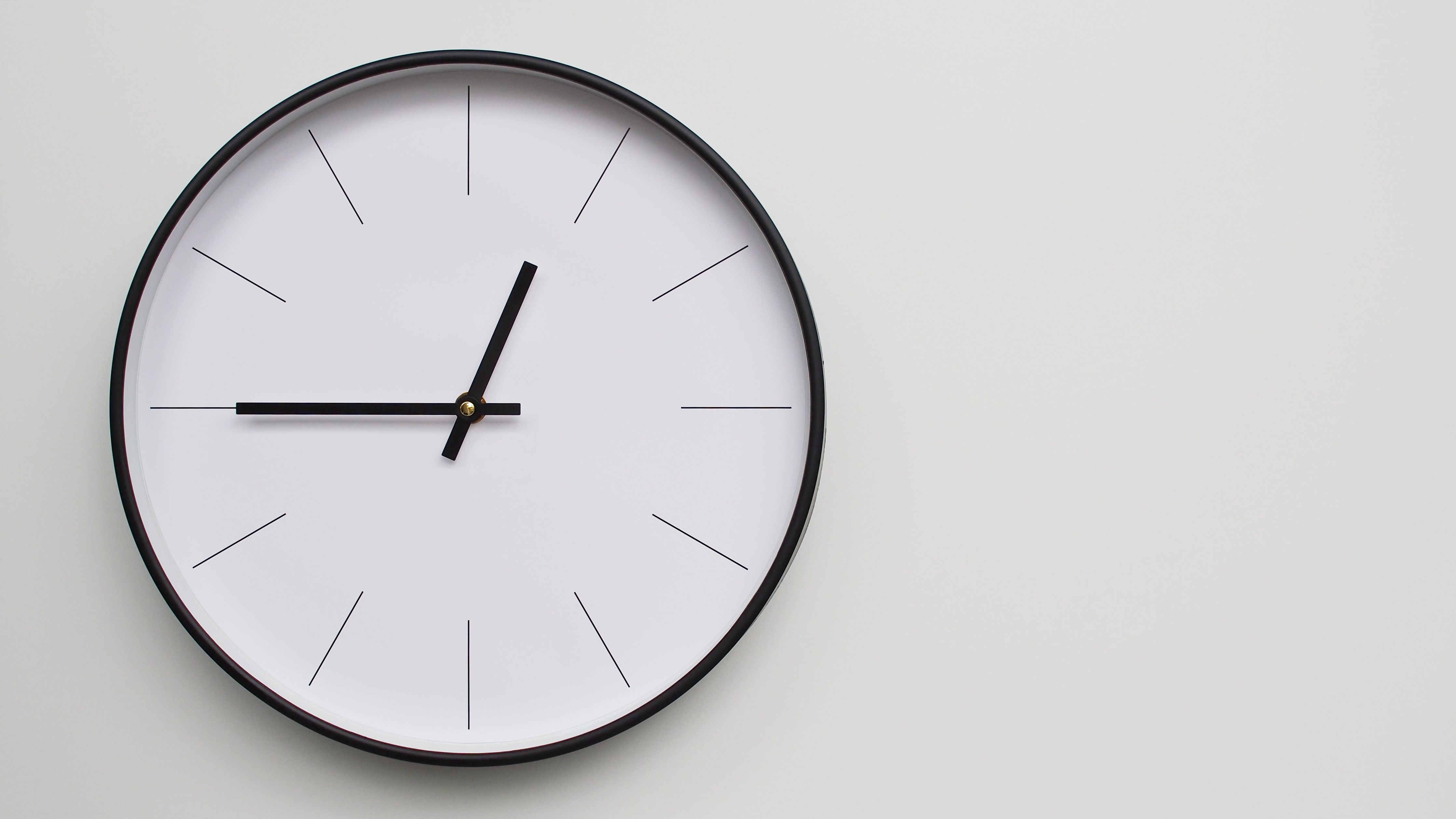 Reloj de pared que marca las 00.45 horas sobre una superficie de madera blanca: perfecto para la gestión del tiempo y los conceptos de programación