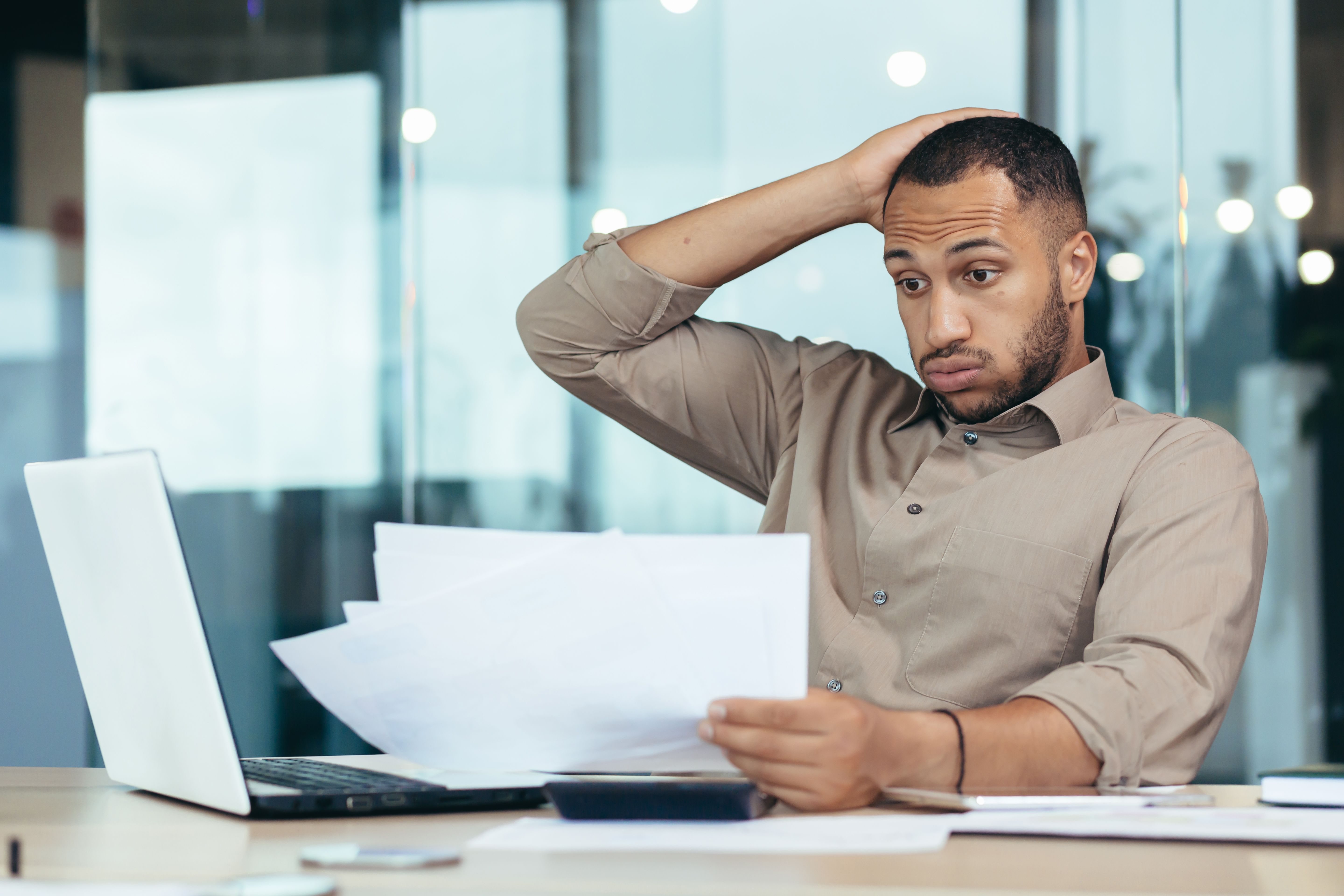Worried African American man student holding papers in hands, bad exam results, refusal of admission