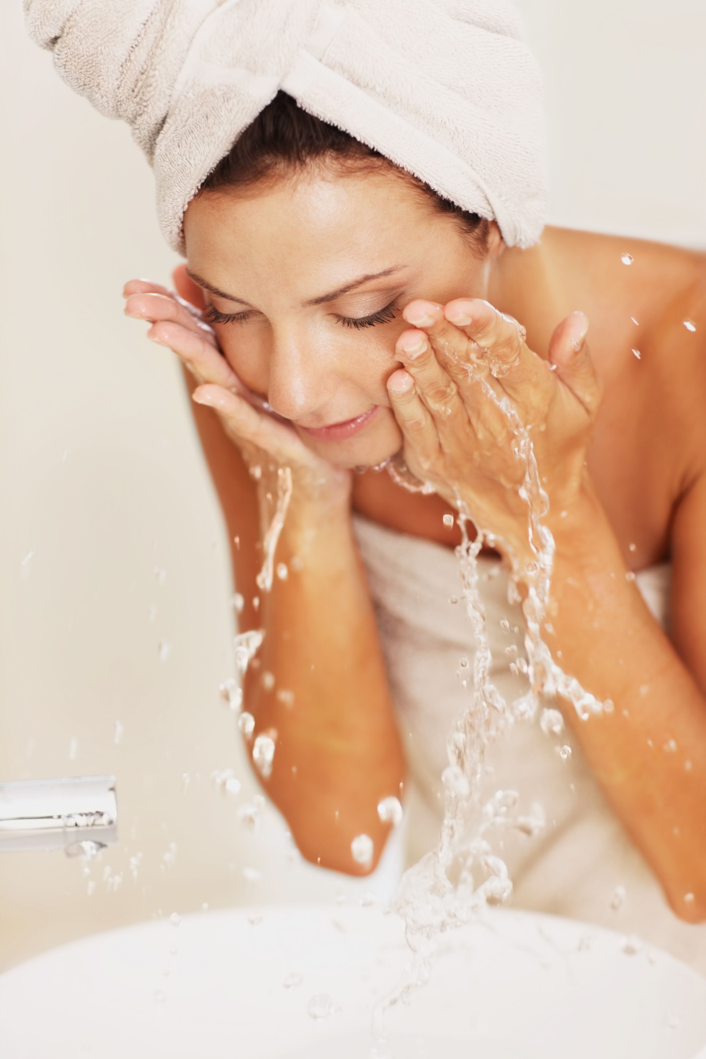 Young woman washing her face with water