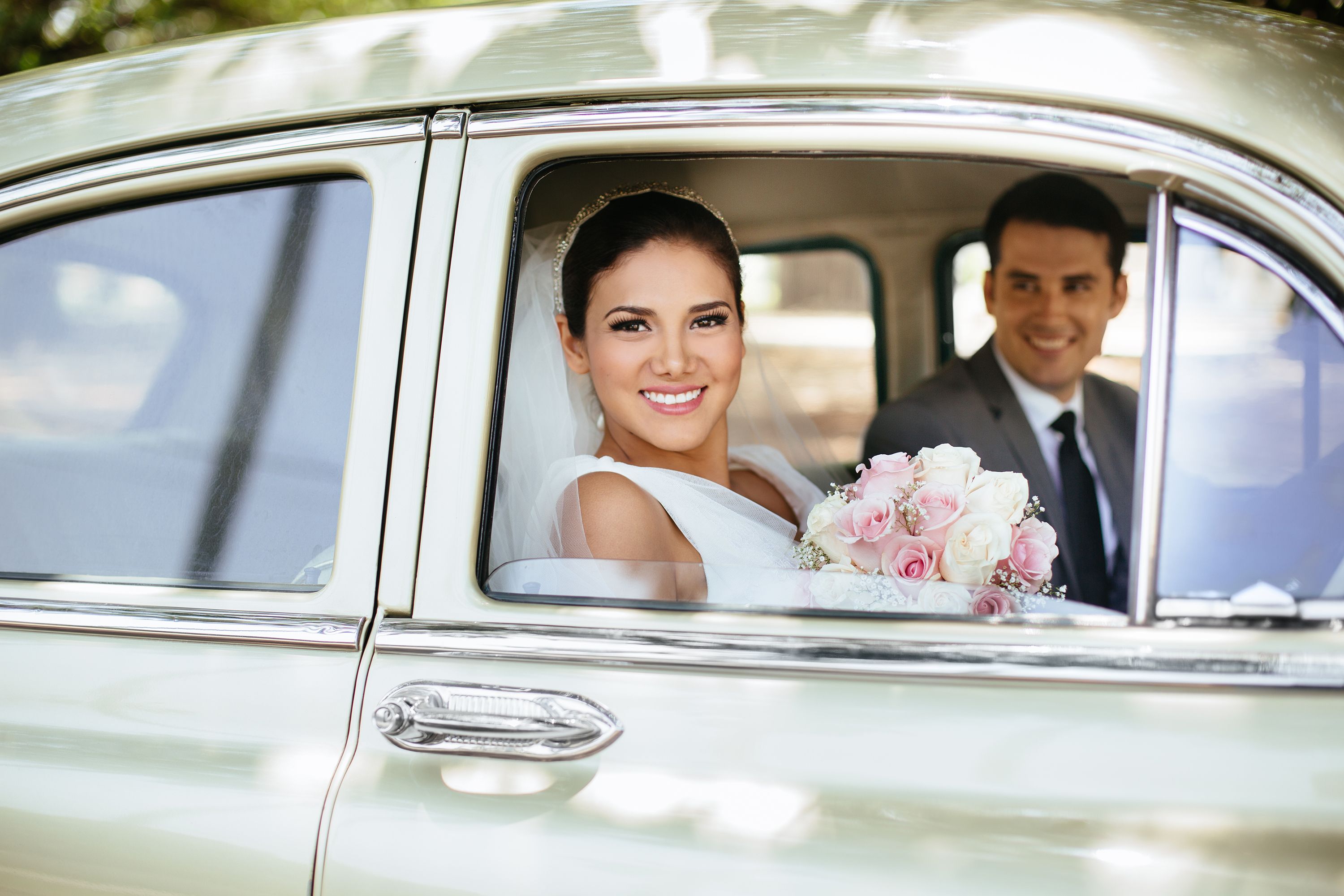Hispanic bride and groom looking out of a classic car Hispanic bride and groom looking out of a classic car