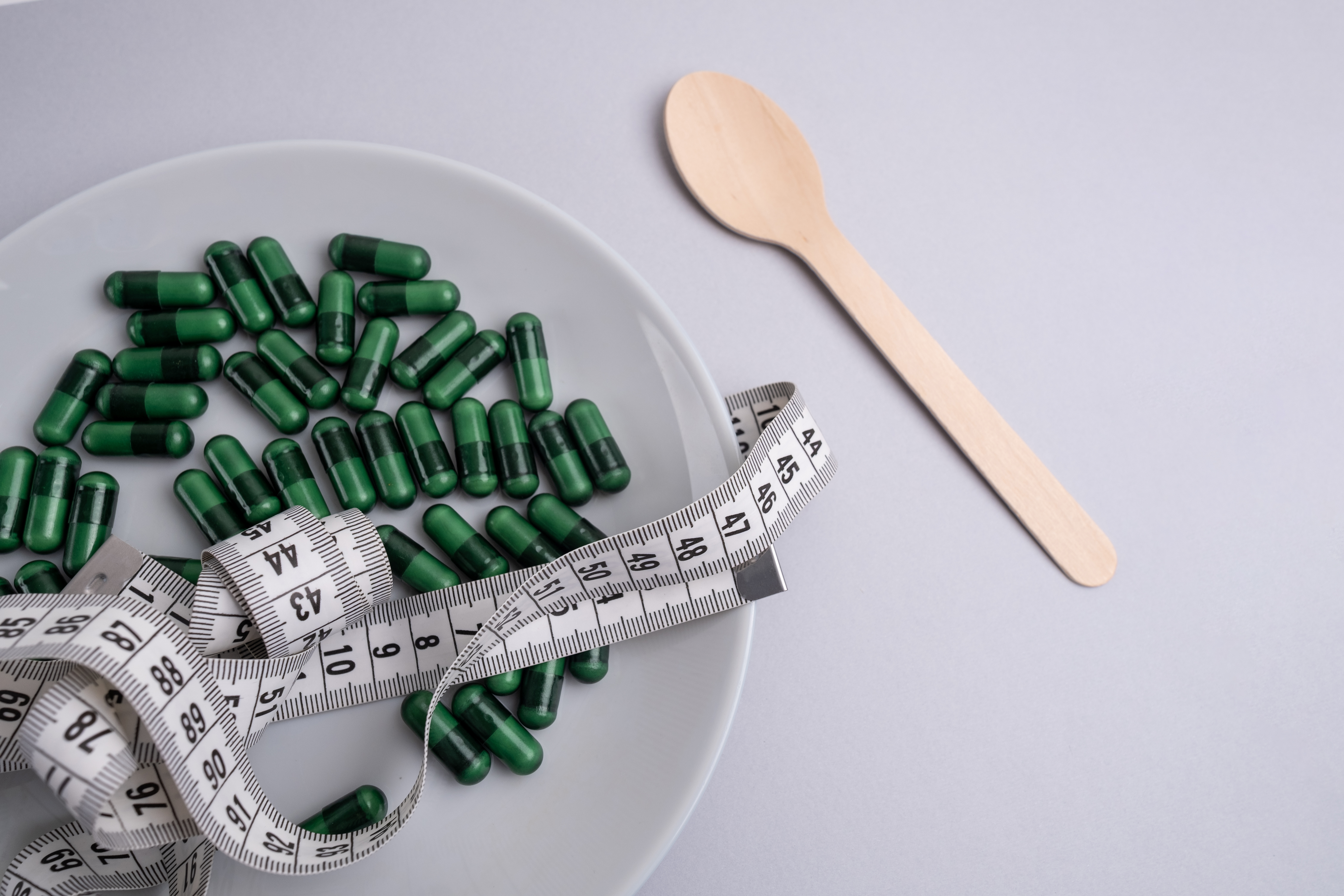 Measuring tape and tablets, vitamins on a colored background with space for text. Concept of losing weight, dieting, burning fat, healthy eating Measuring tape and tablets, vitamins on a colored background with space for text. Concept of losing weight, dieting, burning fat, healthy eating