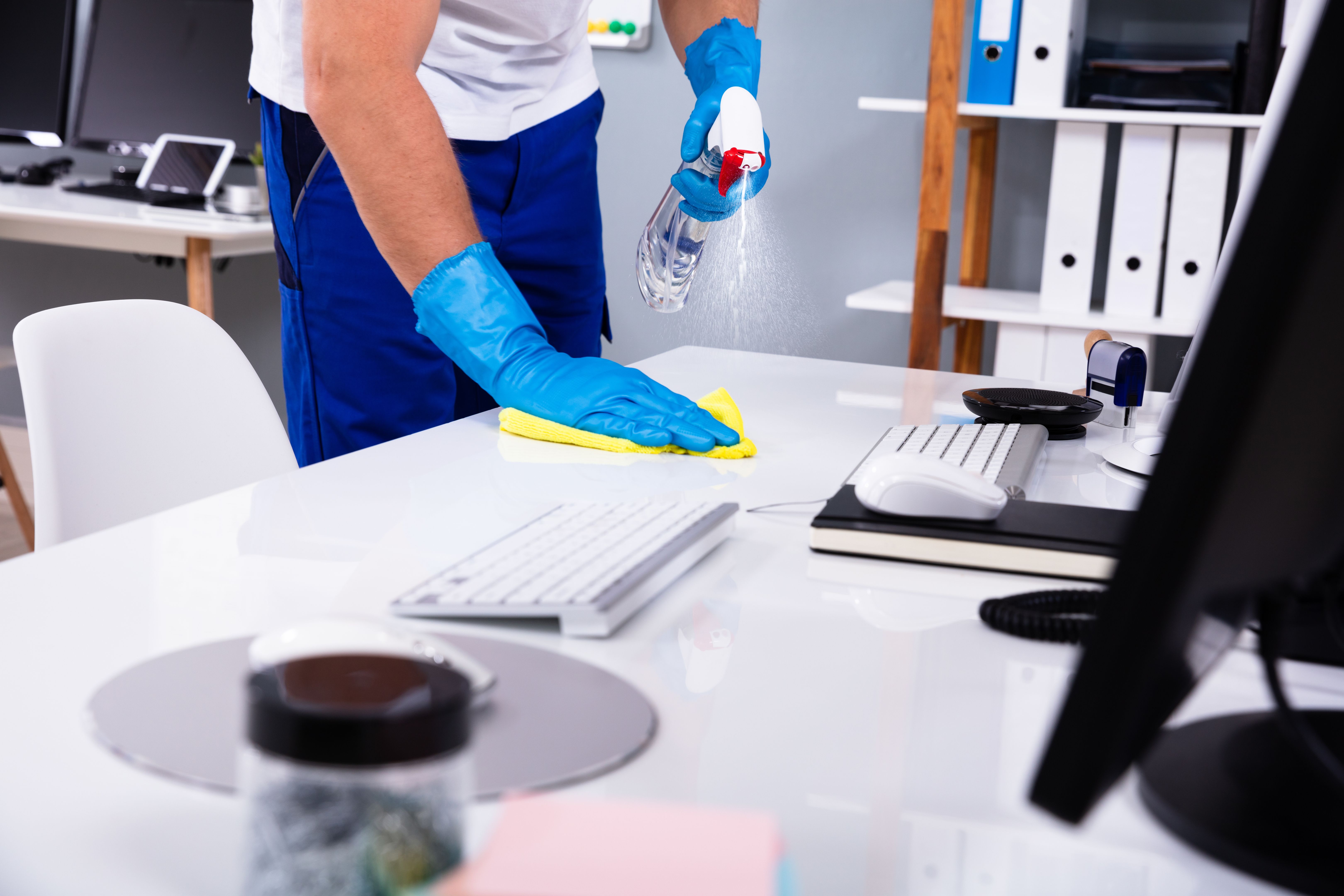 Janitor cleaning white desk in office Janitor cleaning white desk in office