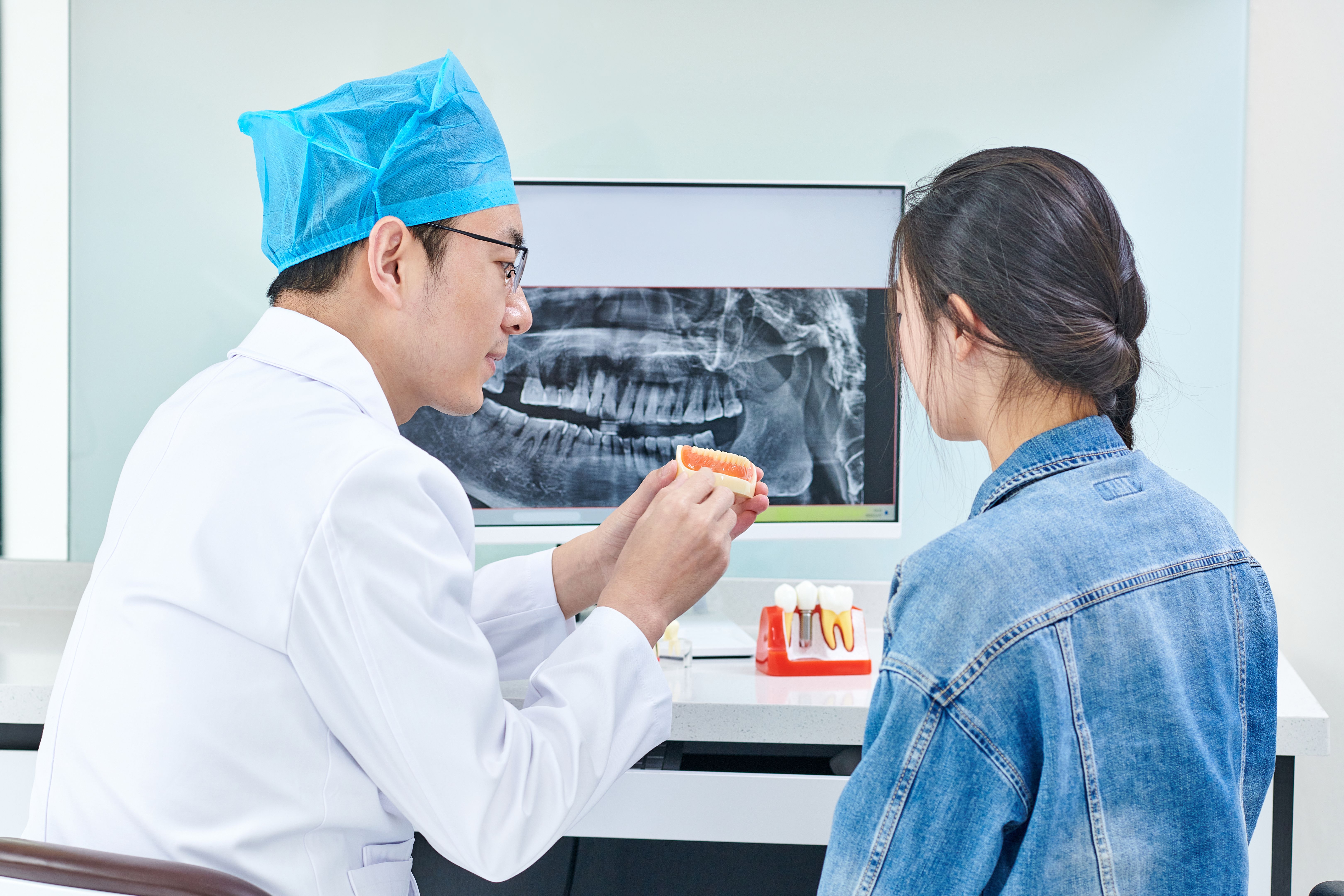 Asian Dentist and Patient Discussing Solution while Using Computer