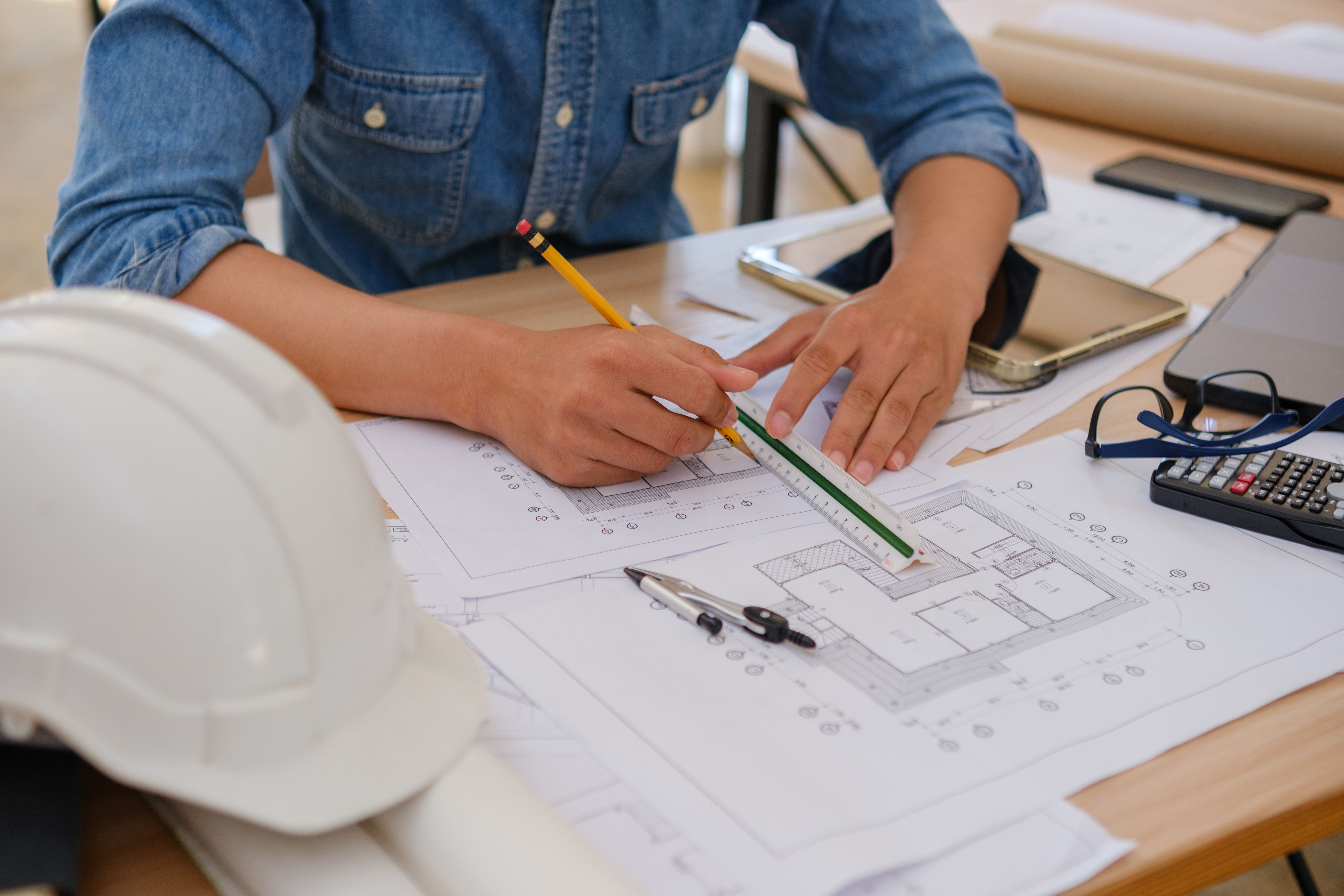 Architect and engineer drawing blueprints with a pencil and ruler at a work desk