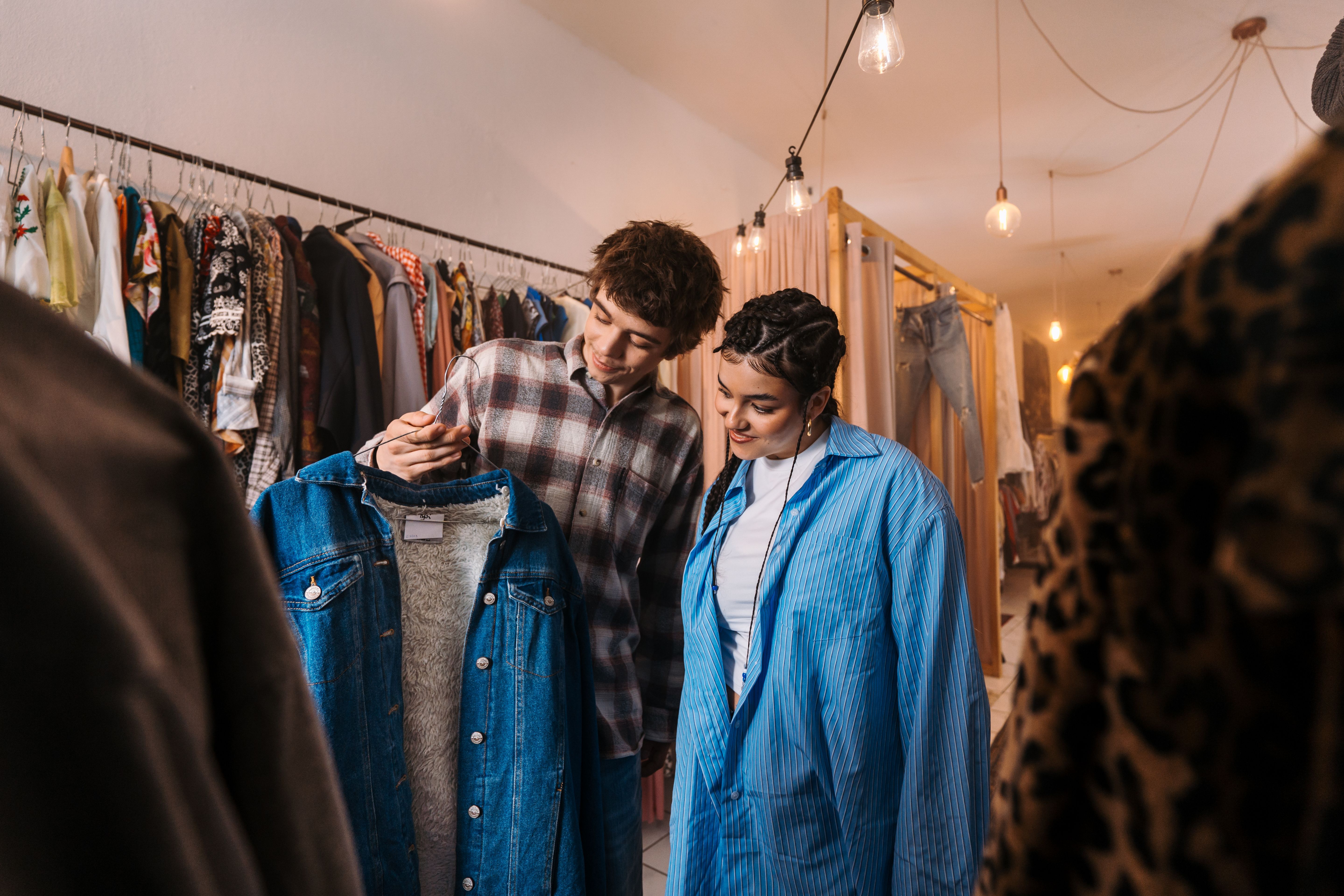 Fashion Enthusiasts Discovering and Exploring Vintage Clothing in a Stylish Boutique