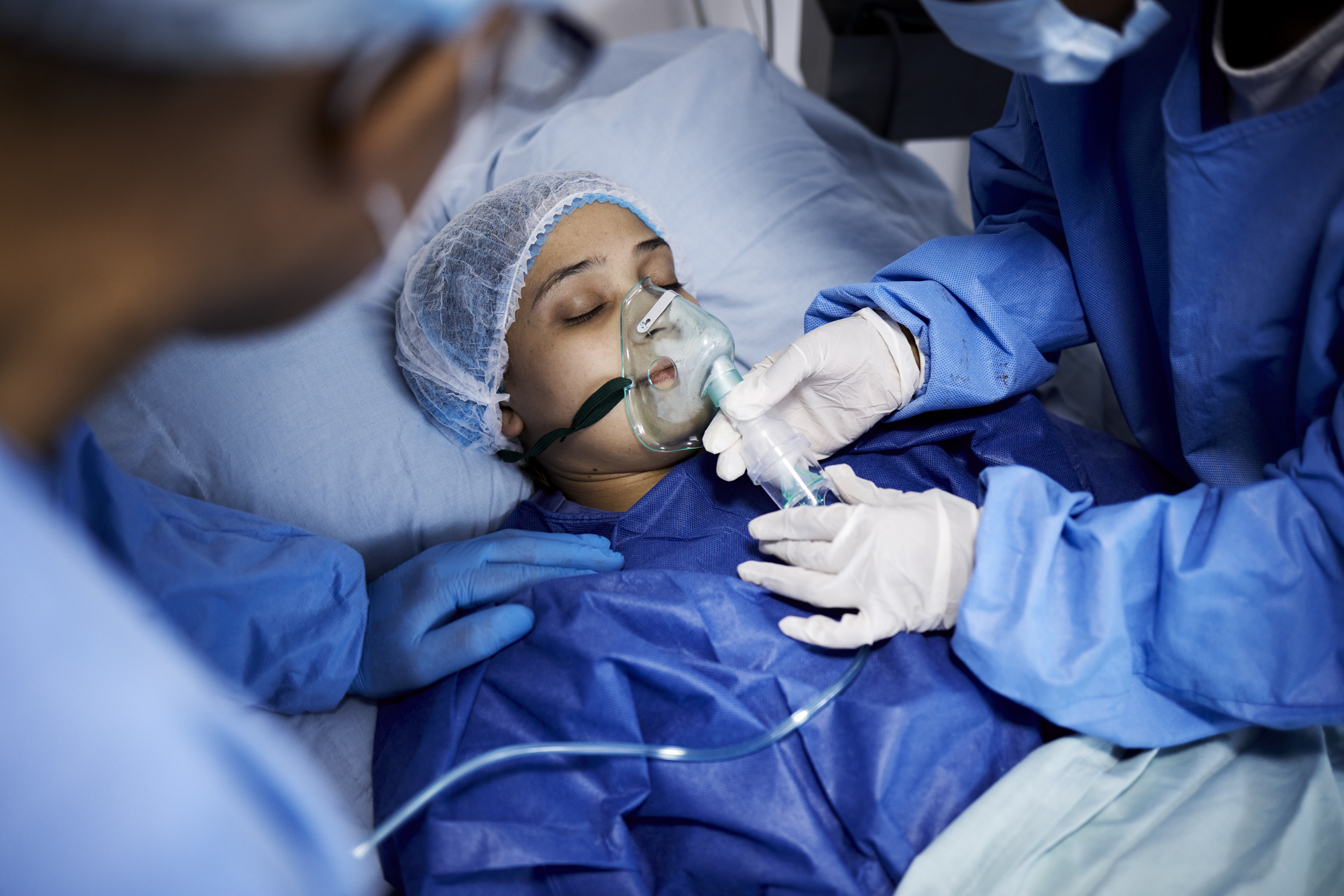 Doctor, hospital bed or sick woman with an oxygen mask, respiratory or operation for healthcare recovery. Medical surgeon, anesthesia or patient with breathing equipment for ventilation in emergency