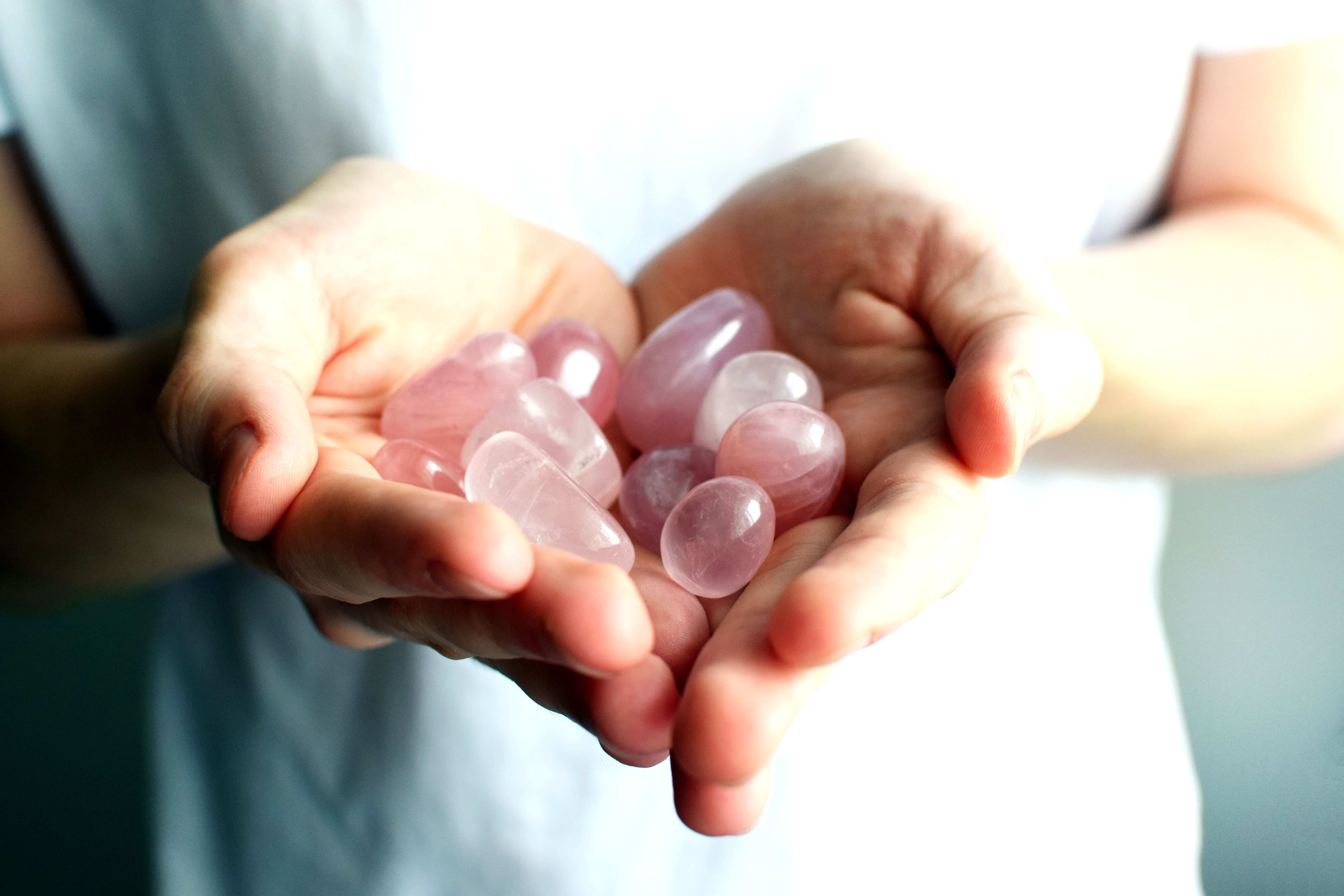 Beautiful gemstones in hands. Polished rose quartz stones close-up. Healing crystals.