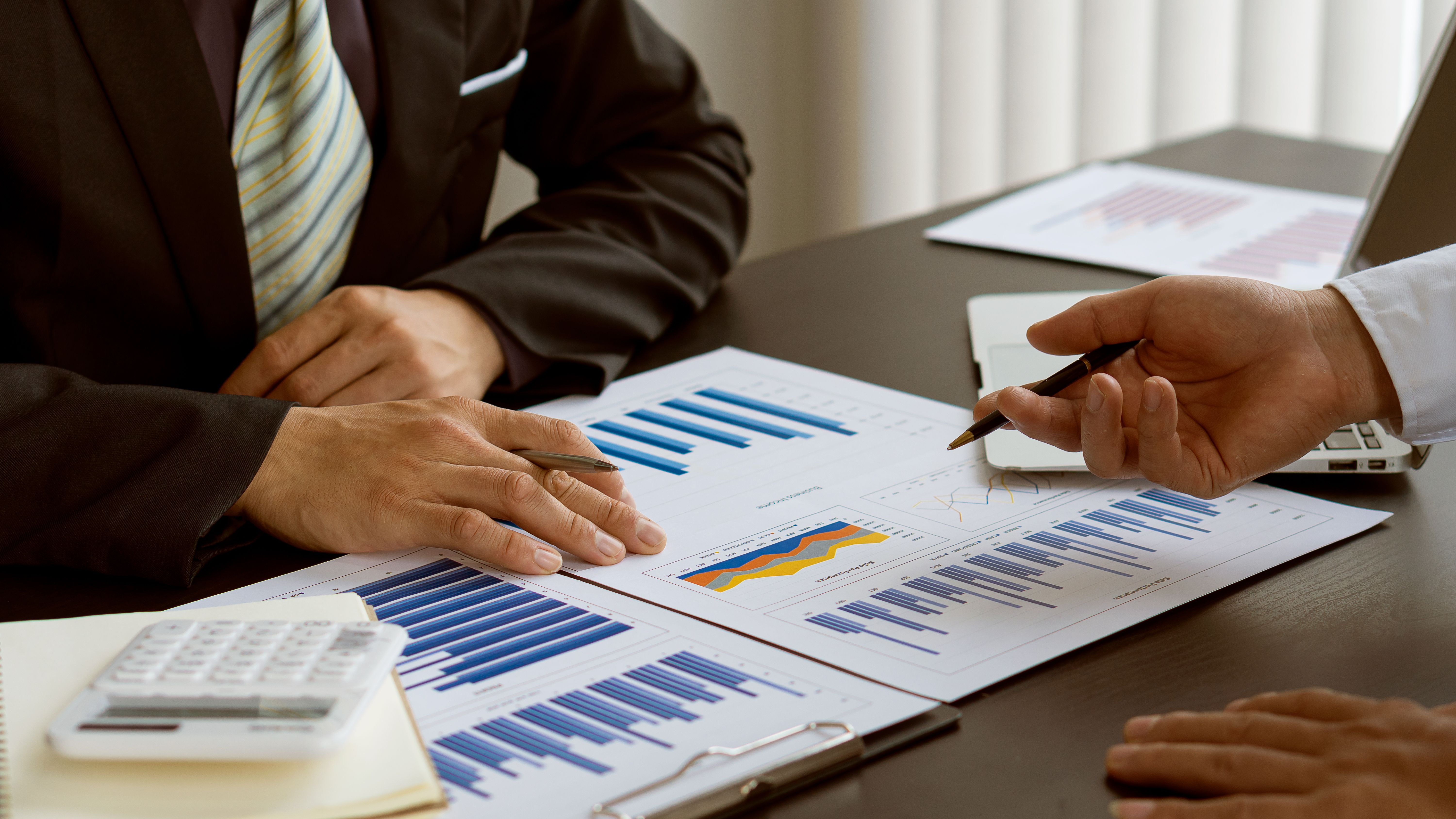 Młody przedsiębiorca pracuje na laptopie i sporządza wykresy dokumentów w ramach analiz i obliczeń firmy.