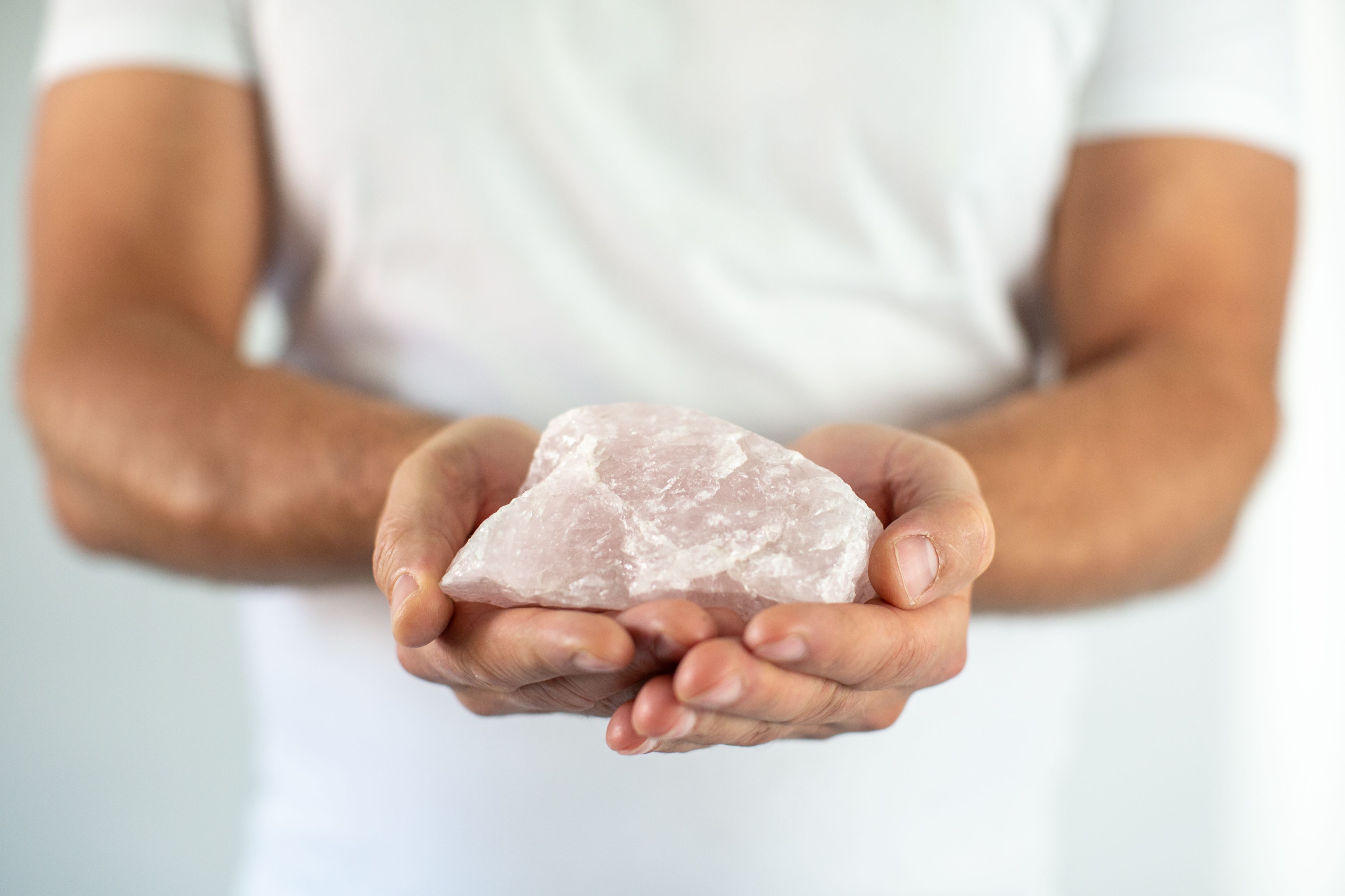 Man's hand holds a rose quartz