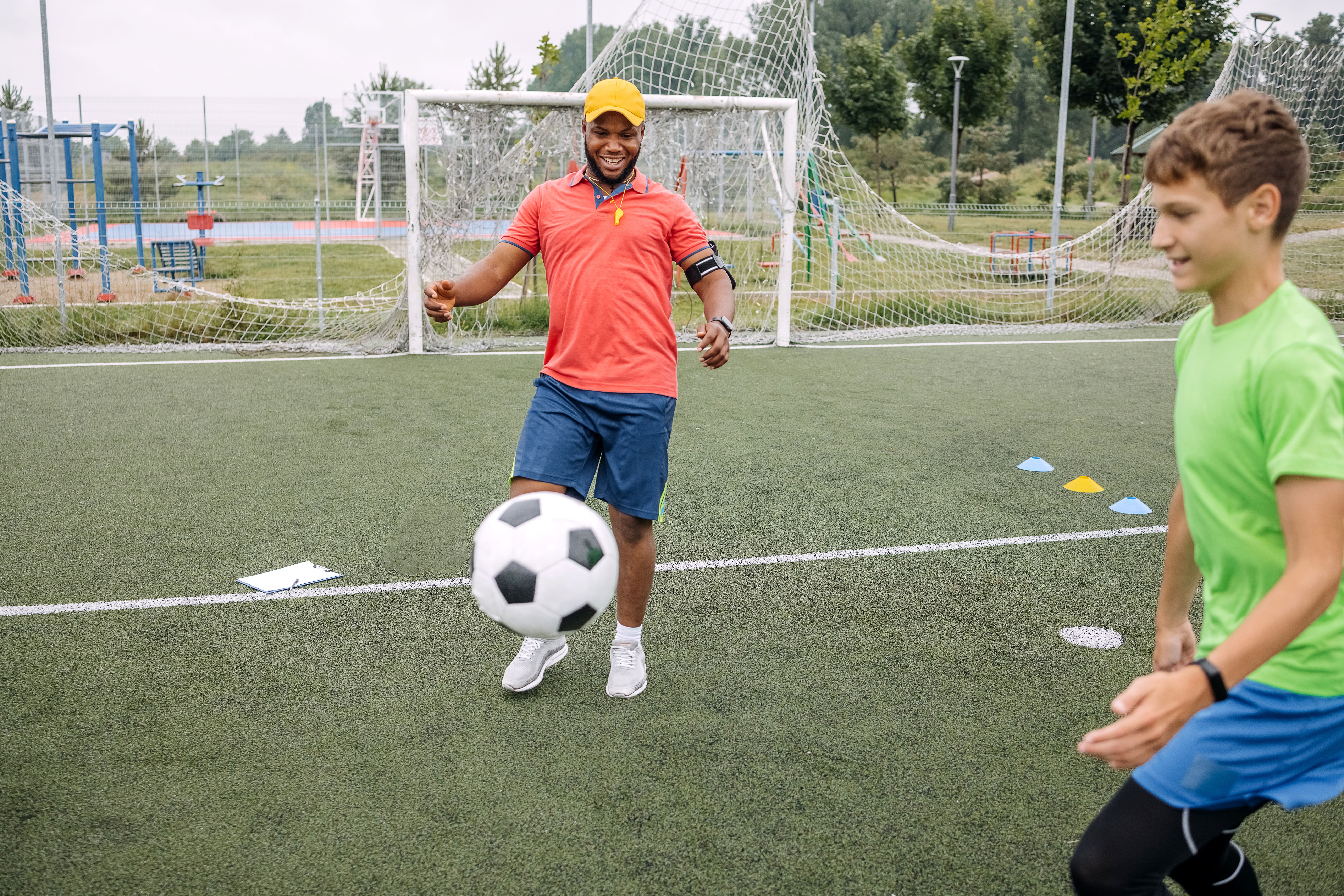 Boy having individual soccer training by the black coach