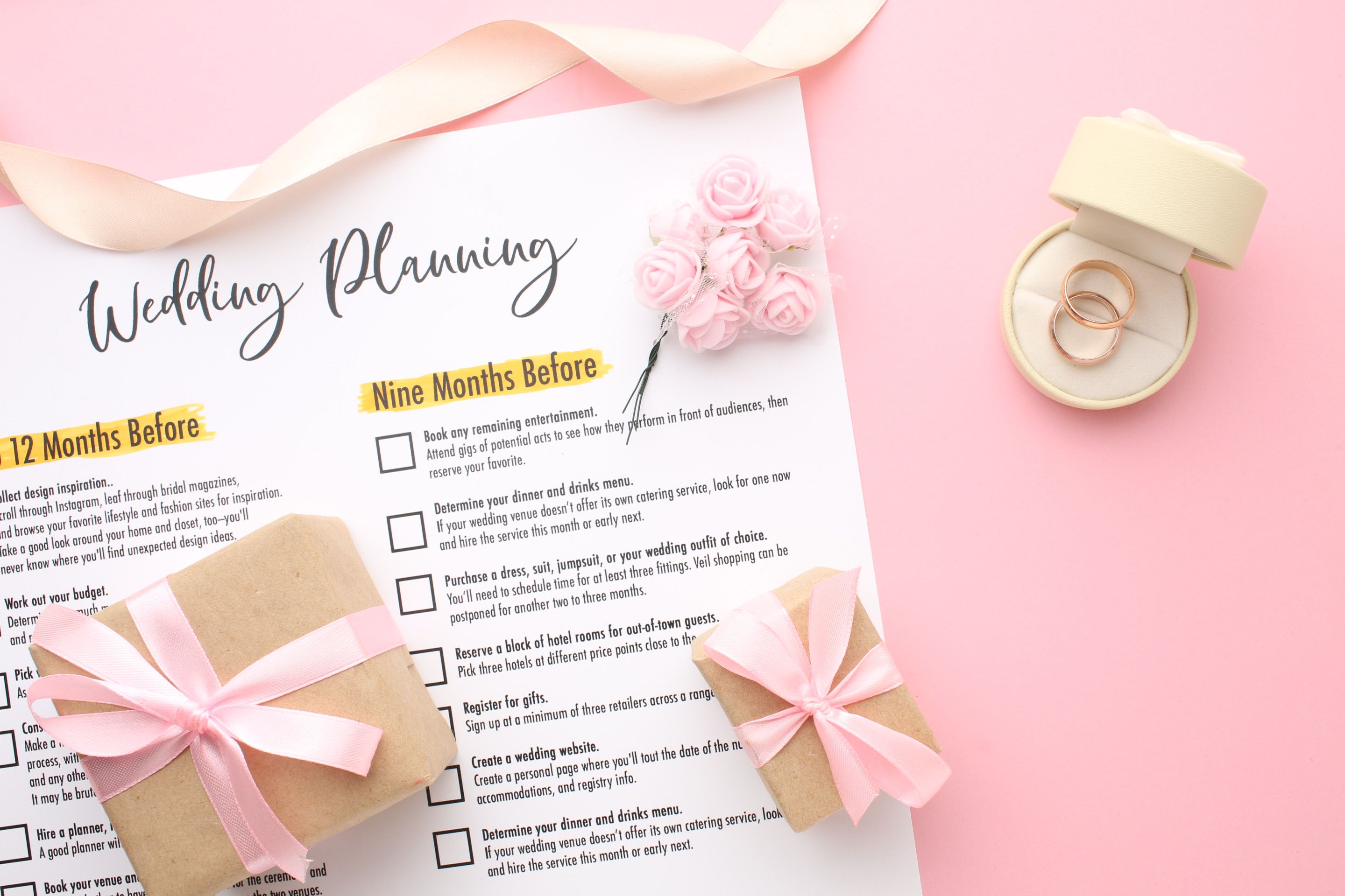 Wedding to-do list top view. Gift boxes, wedding planning calendar and various wedding trivia on a pink rustic table. Background for organising the commemorative date