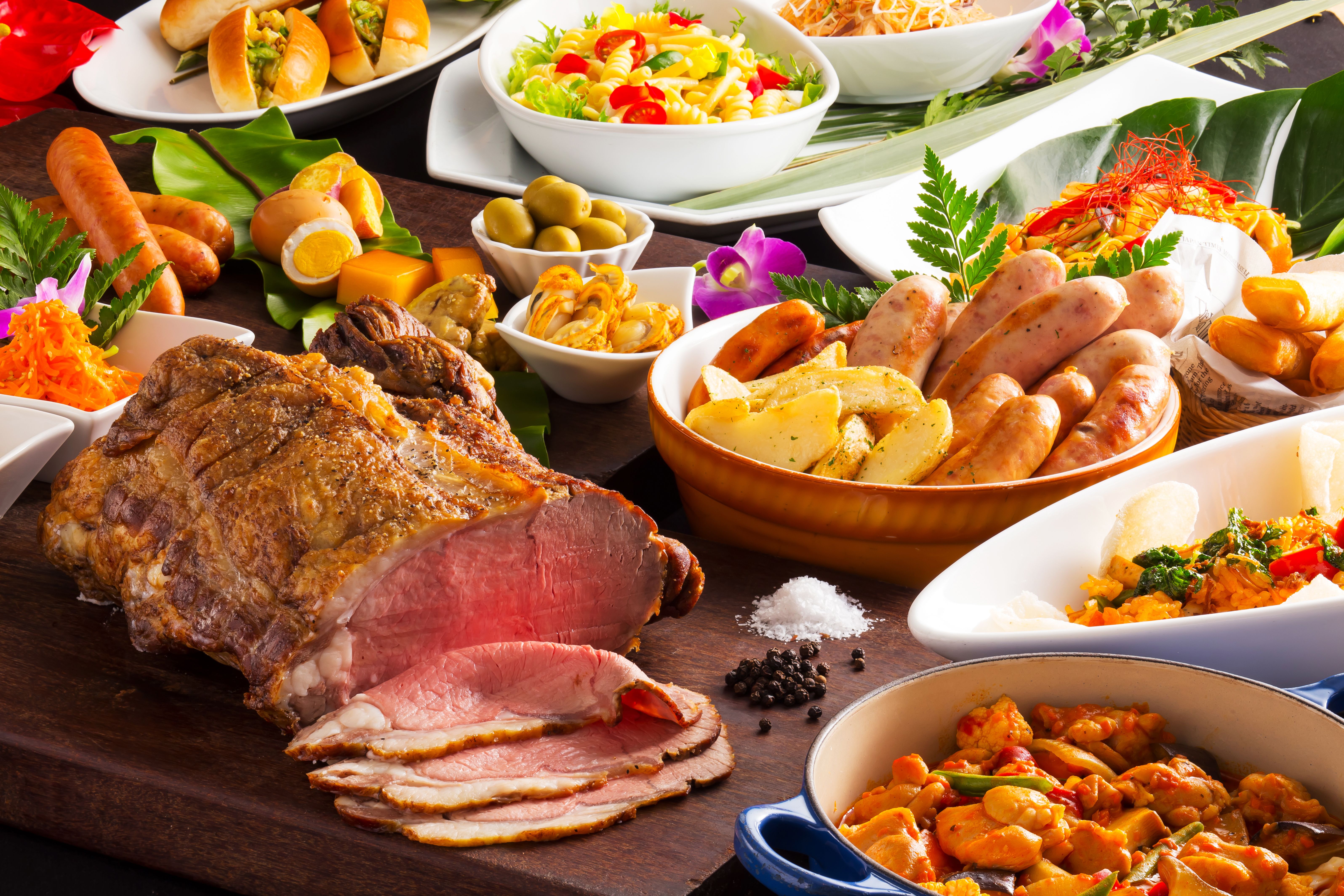 Table of food with grilled beef, sausages, pasta, fried tomatoes