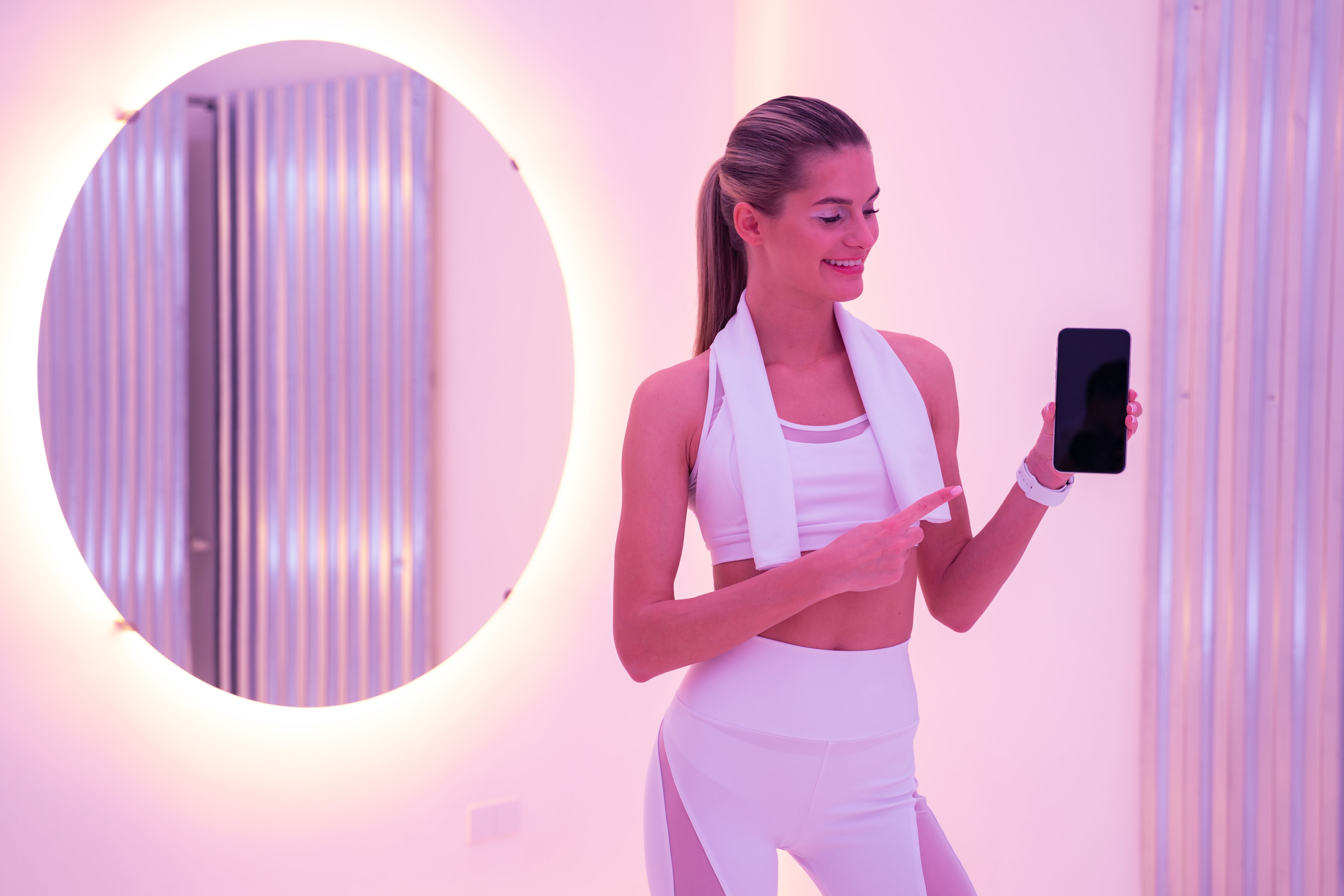 Young female coach showing her phone with blank screen for fitness app Young female coach showing her phone with blank screen for fitness app