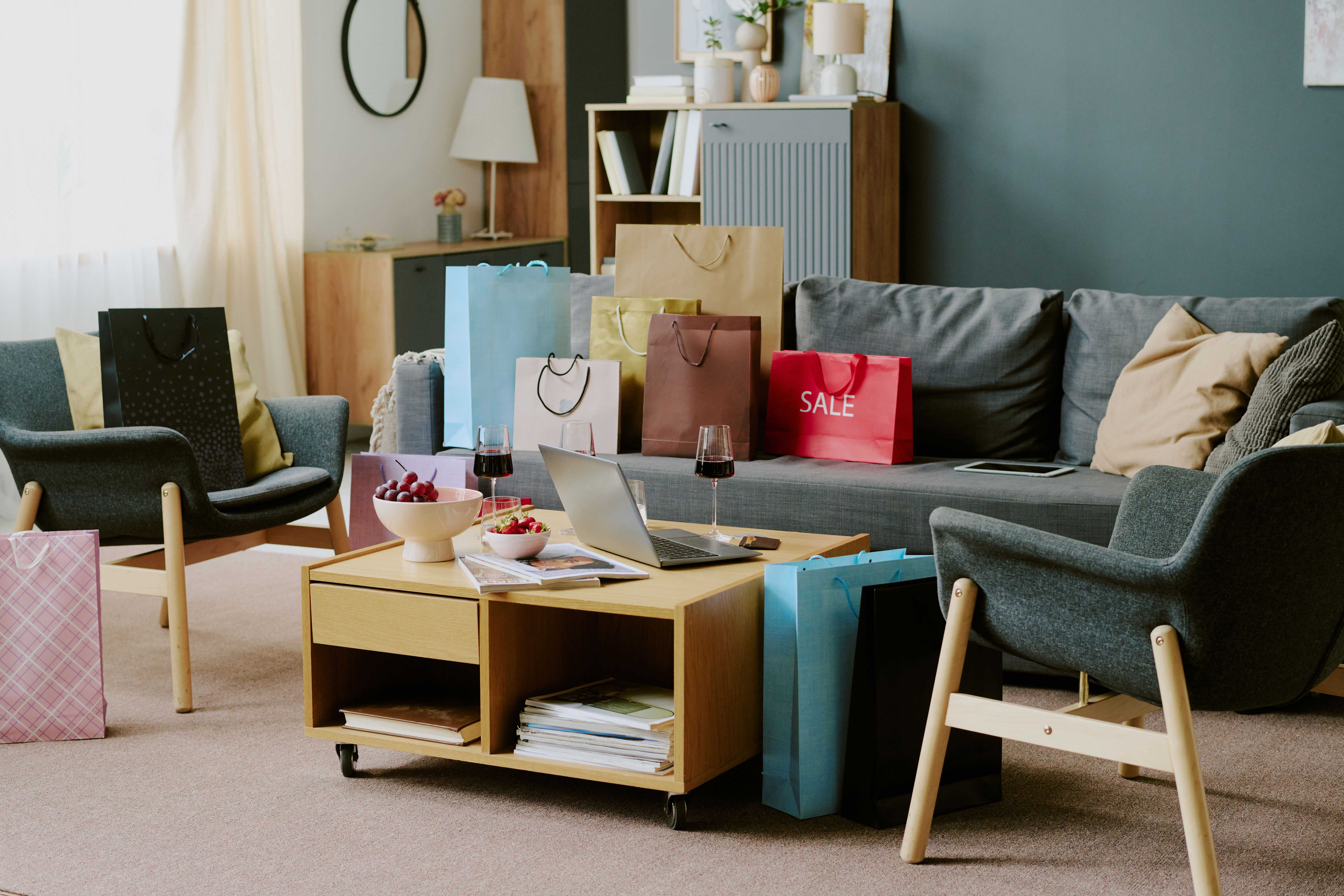Shopping Bags on Living Room Furniture Surrounding Laptop and Wine Glasses