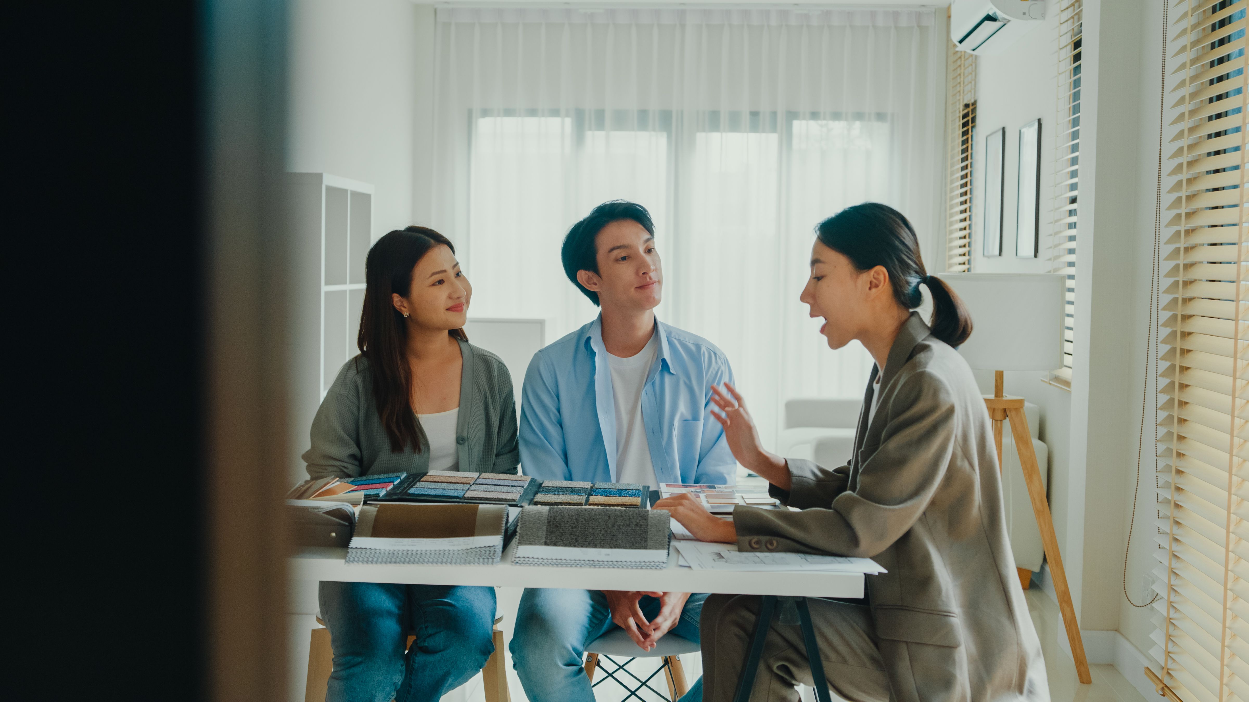 Asian tenants choose colors, patterns, and materials and give them to female interior designer for new house. Happy couple buy real estate for investment.