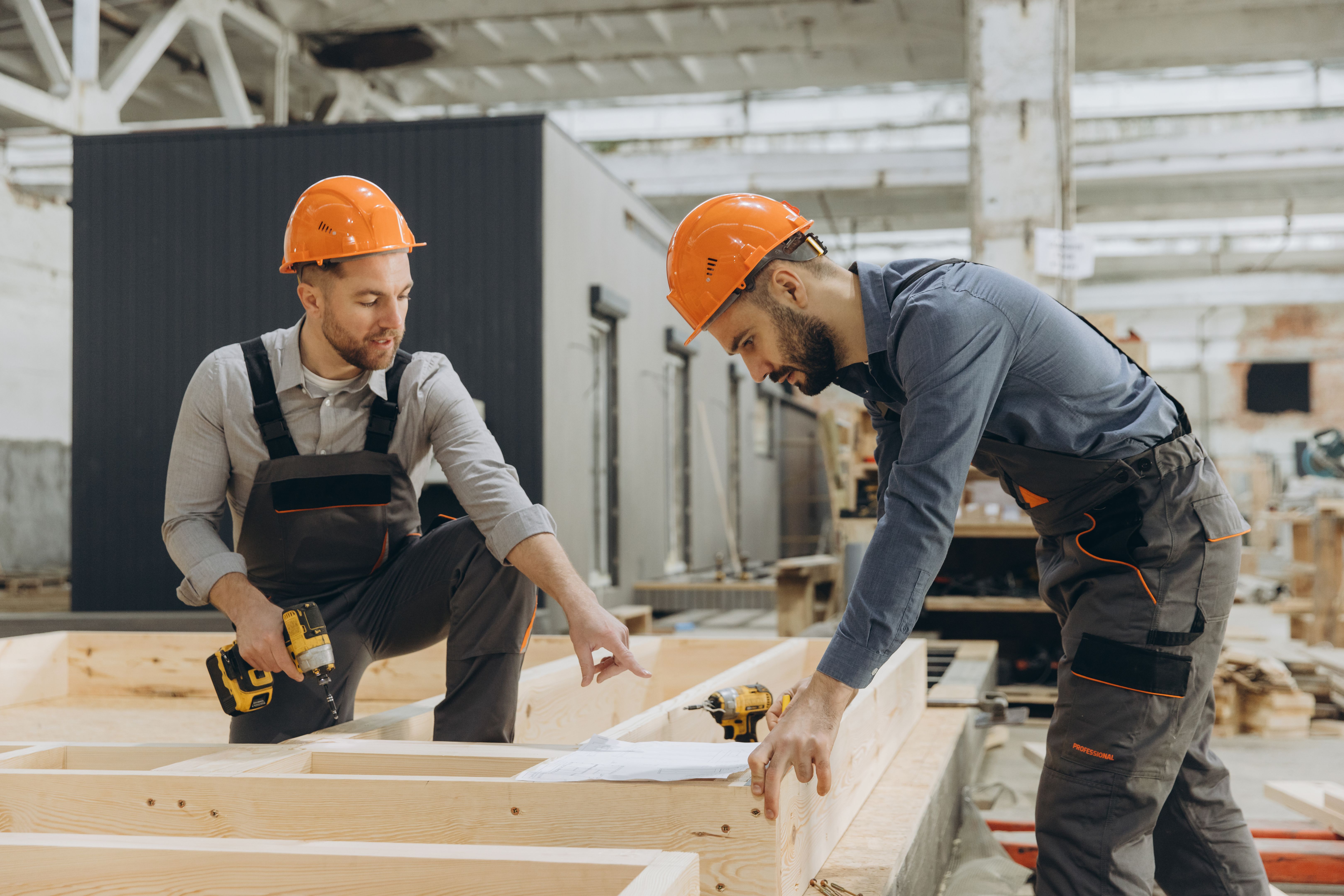 Construction workers building wooden frame in factory