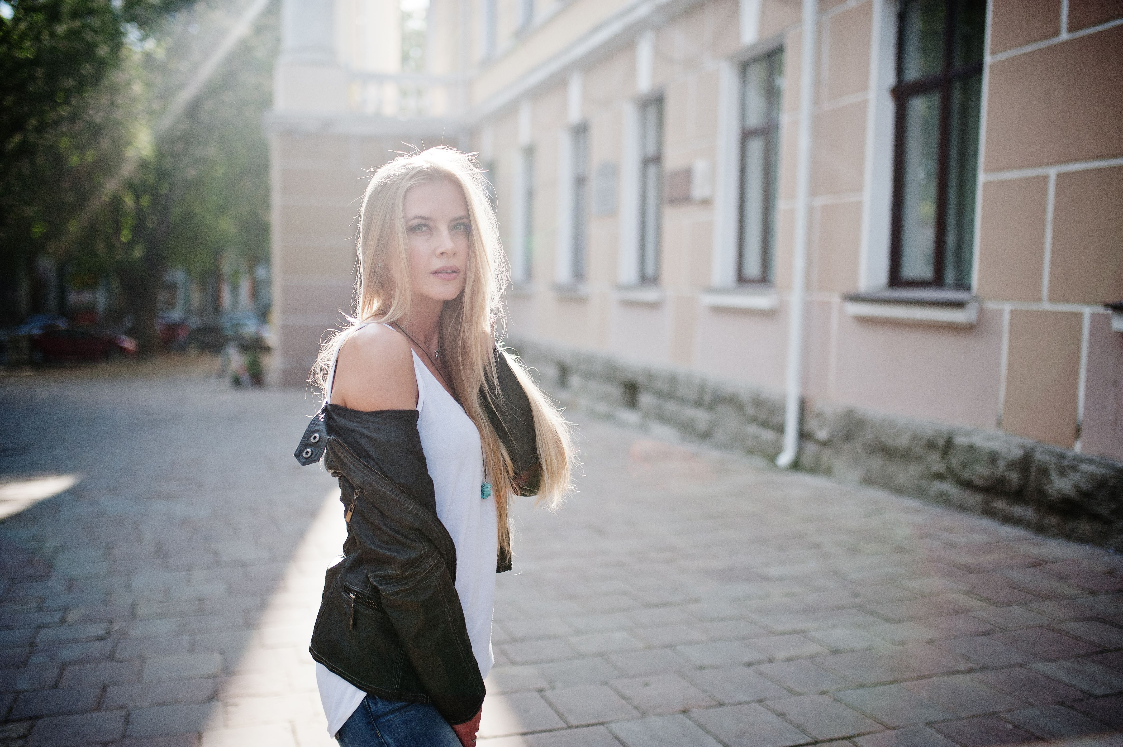 Stylish blonde woman wear at jeans, sunglasses and jacket posed at street on sunshine. Fashion urban model portrait. Stylish blonde woman wear at jeans, sunglasses and jacket posed at street on sunshine. Fashion urban model portrait.