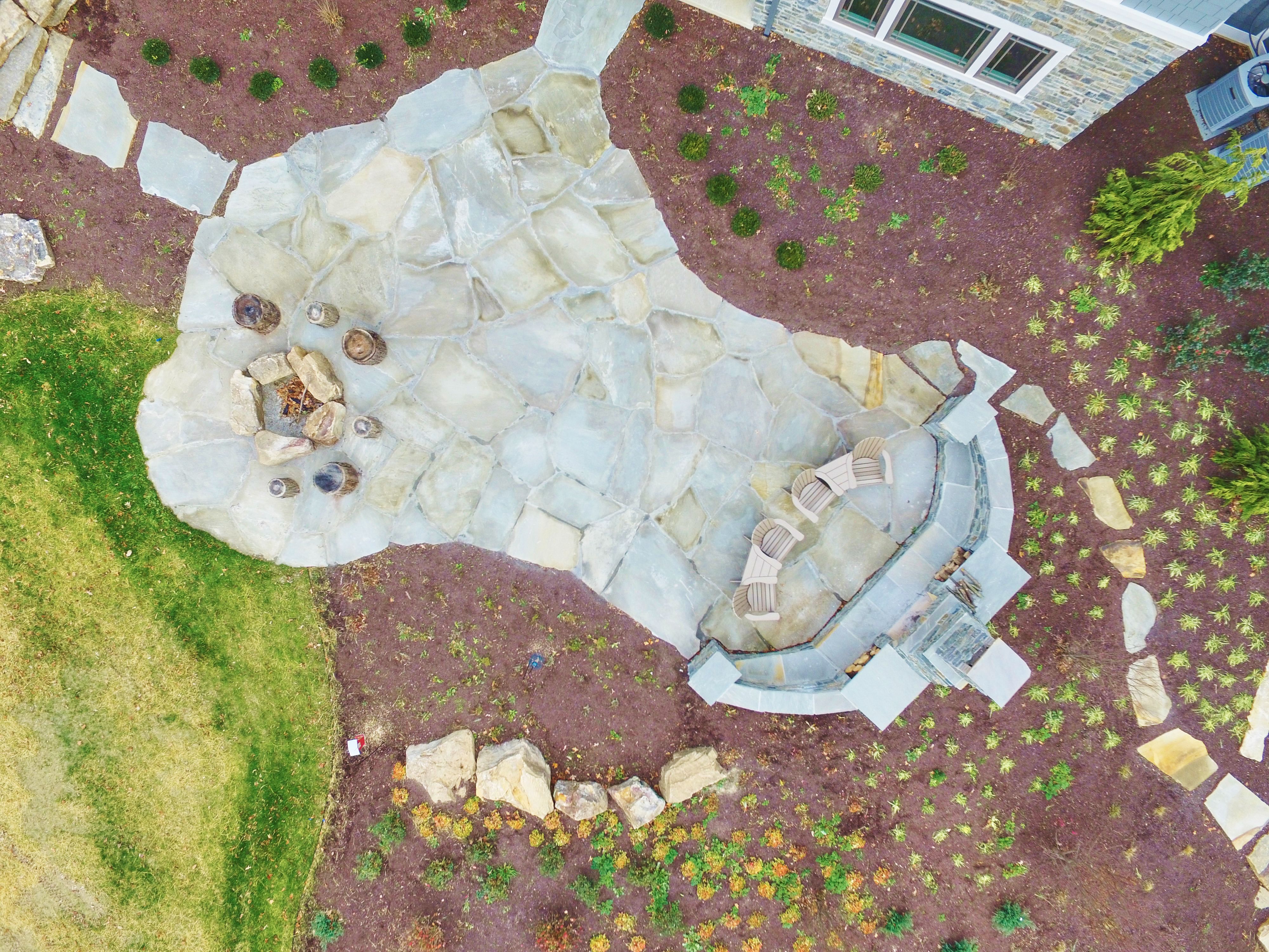 Aerial Top Down of Natural Stone Patio with Fire Pit and Lush Garden