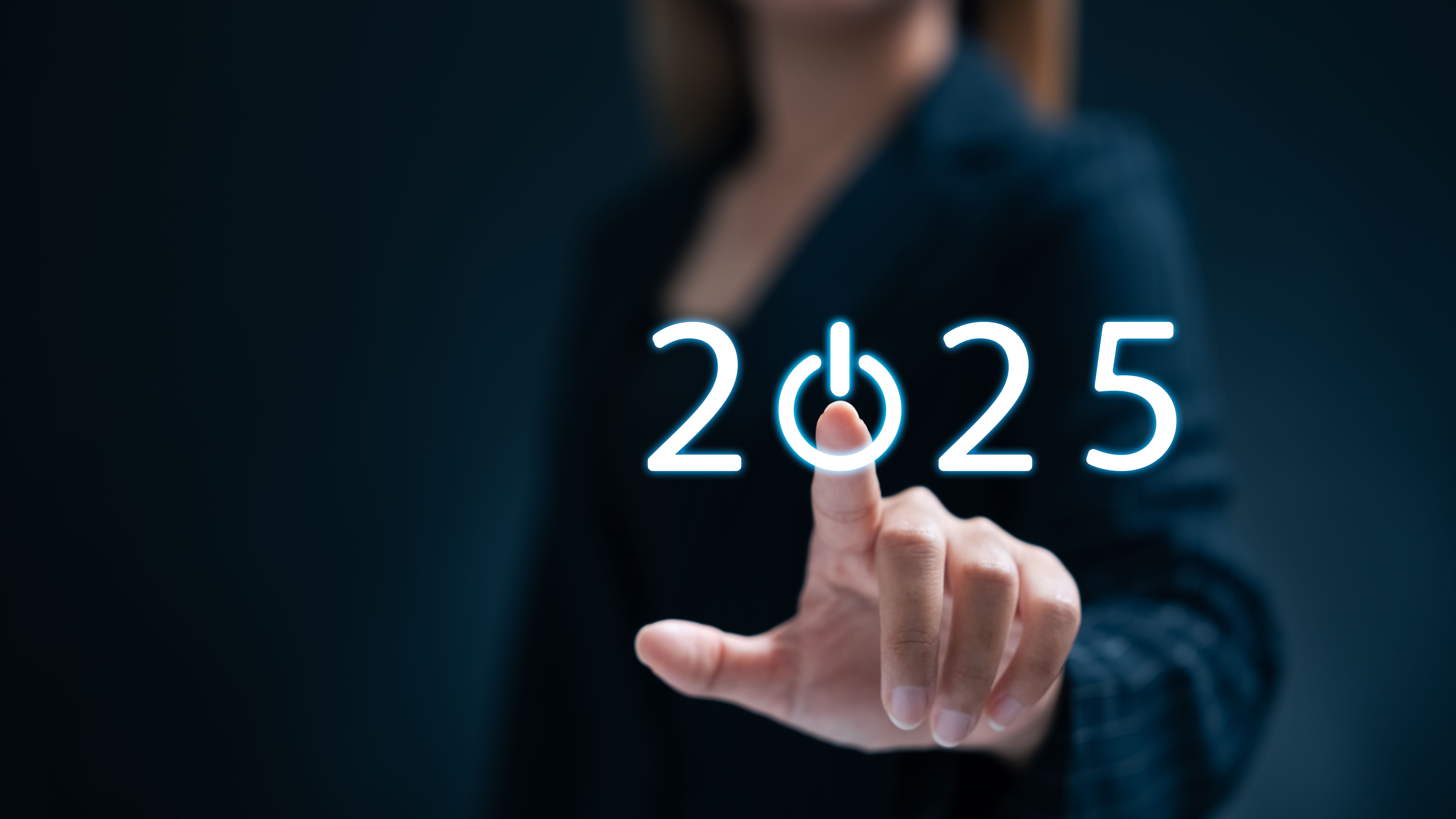 A businesswoman taps a start button for New Year 2025 to set goals and develop strategy.
