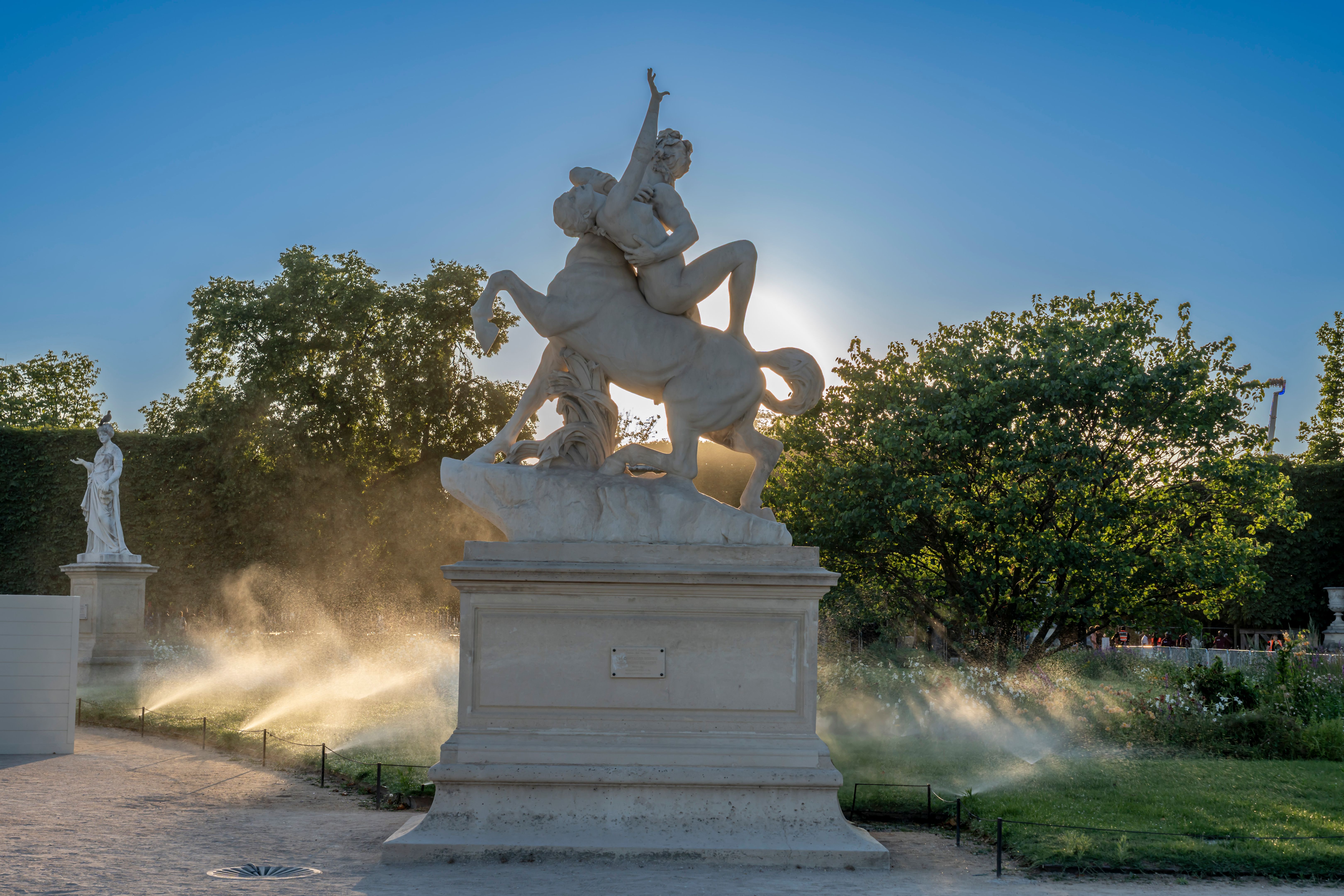 Paris, France - 07 03 2025: One statue in backlight and a watered grove in Tuileries garden