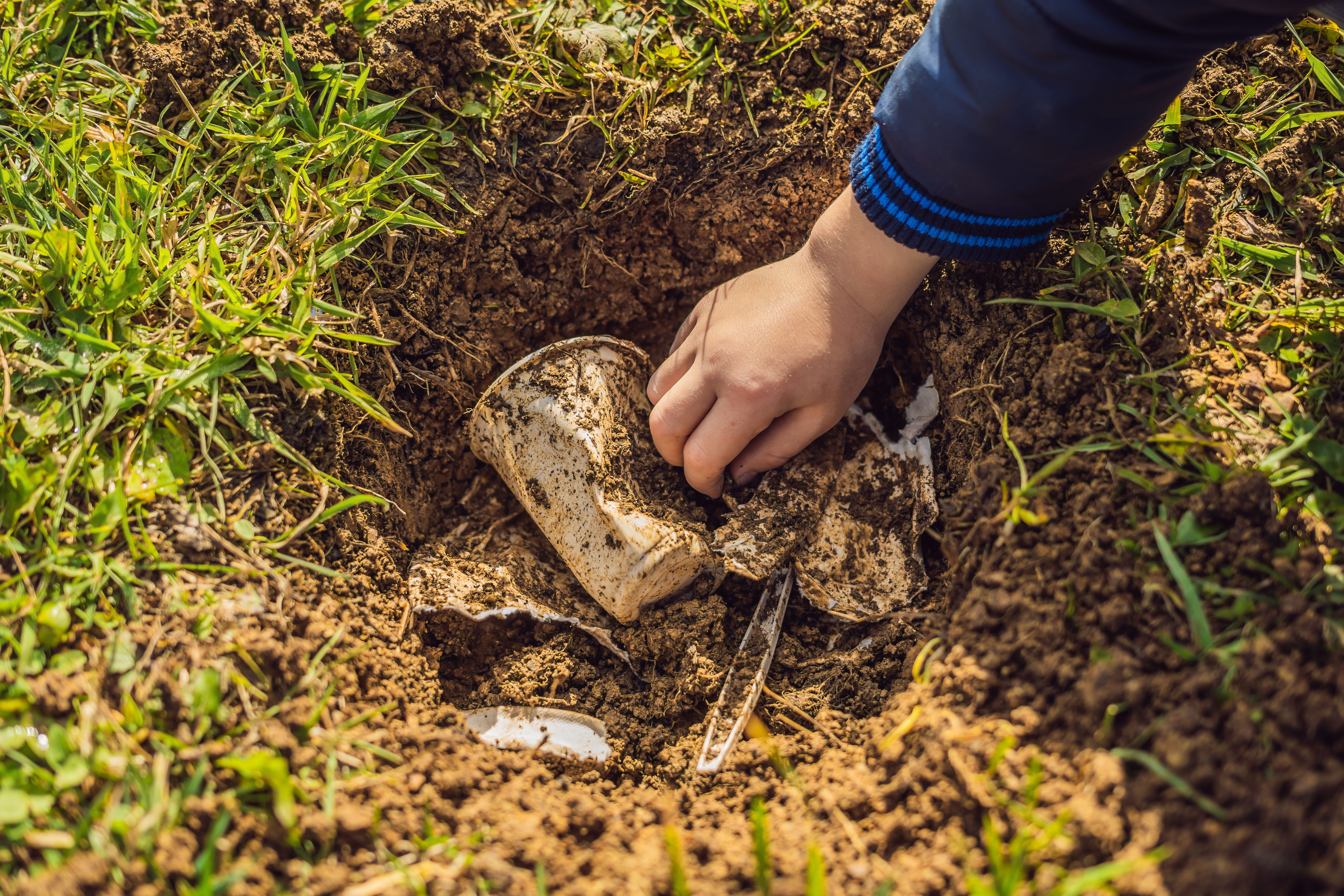 The boy plays recycling. He buries plastic disposable dishes and biodegradable dishes. After a few months, he dug up the dishes and saw that the biodegradable dishes began to decompose and plastic did not