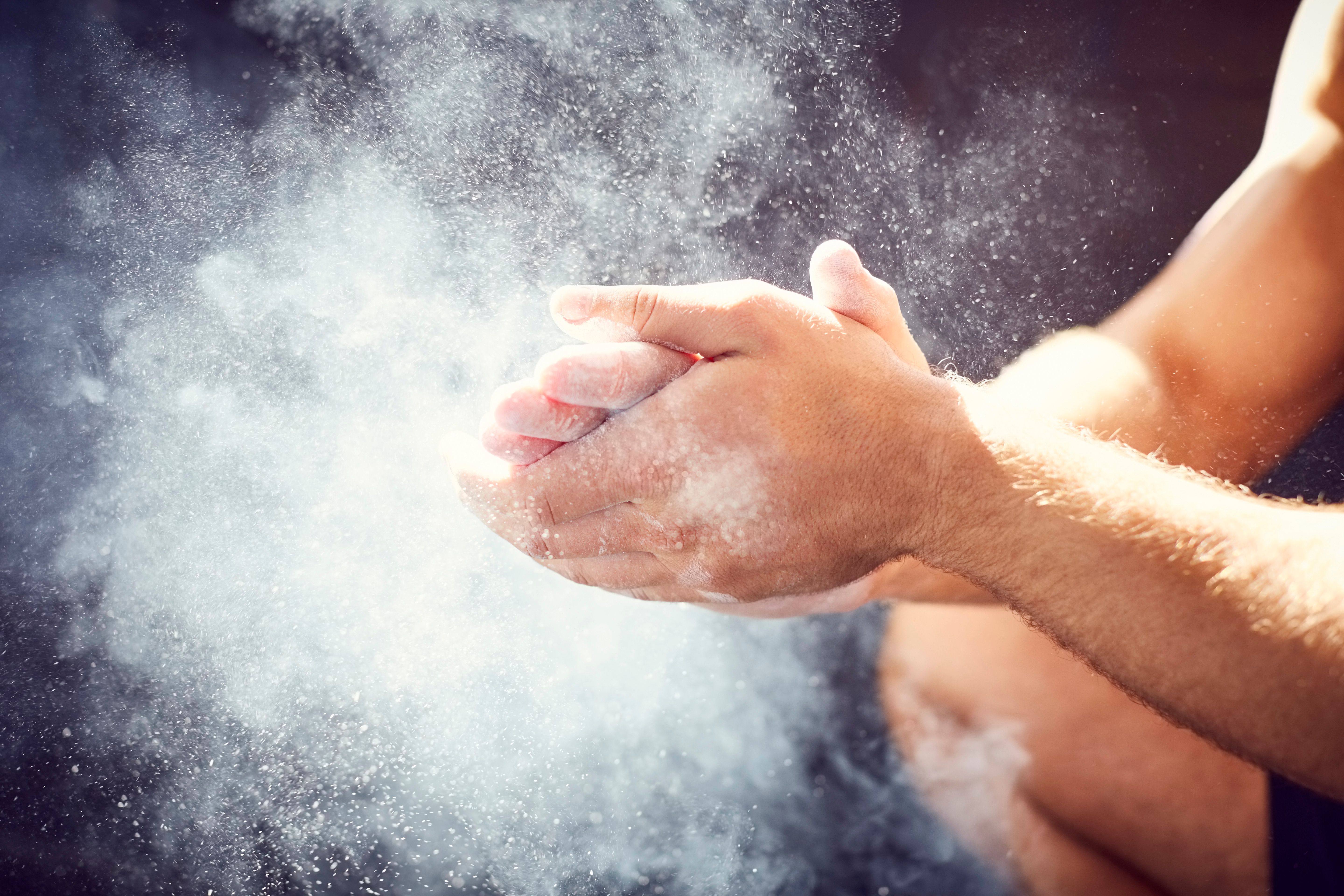 Cropped image of man clapping hands with chalk at gym