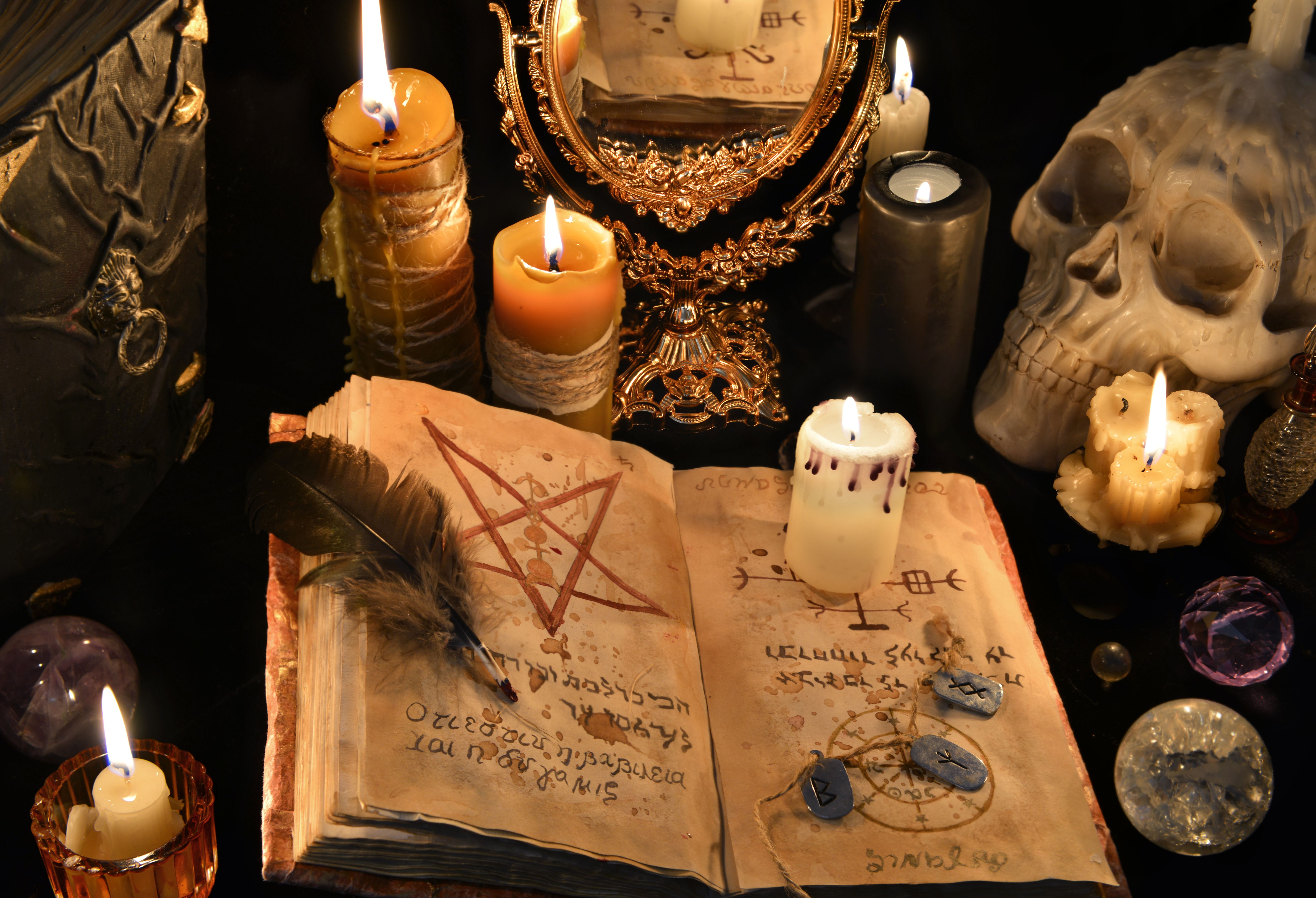 Mystic background with black magic book, candles and mirrow