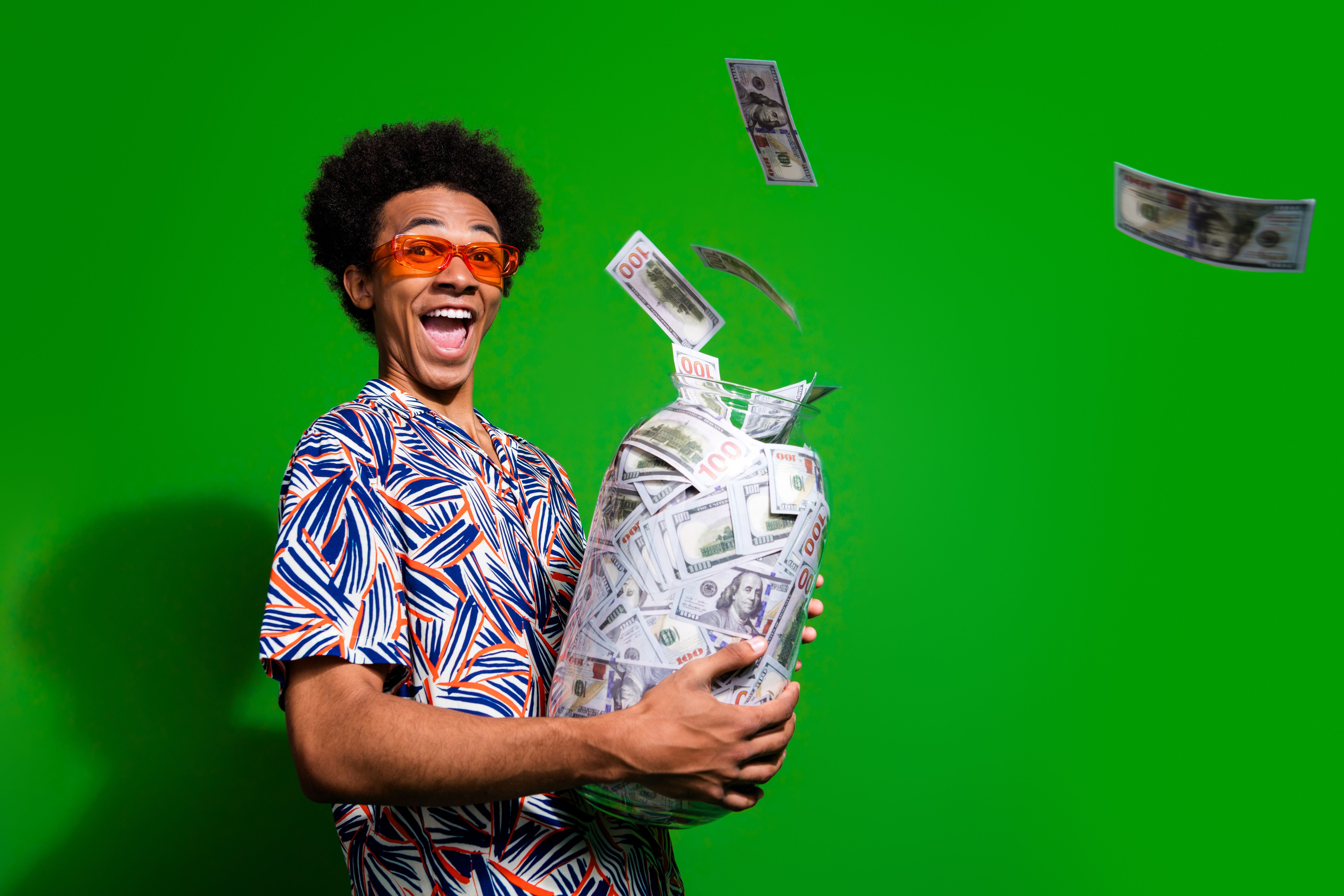 Photo of excited impressed man dressed print shirt dark glasses collecting cash glass jar empty space isolated green color background
