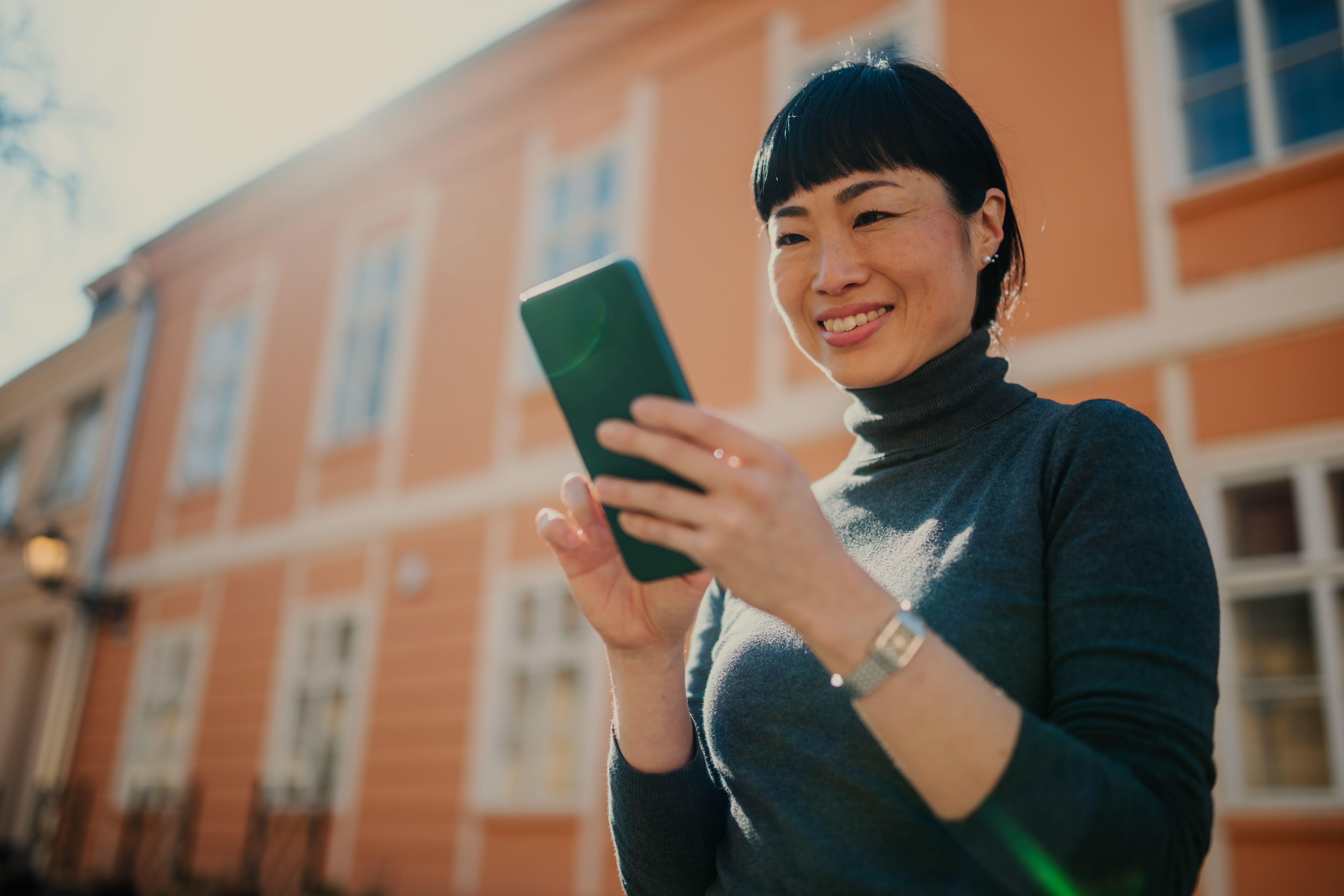 Smiling asian woman using smartphone in urban setting
